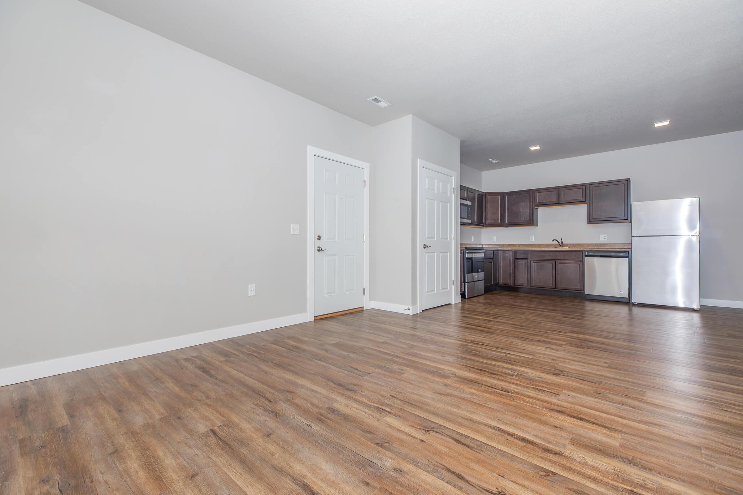 Open-concept living and kitchen area with hardwood-style flooring at The Groves on Devils Glen apartments in Bettendorf, IA