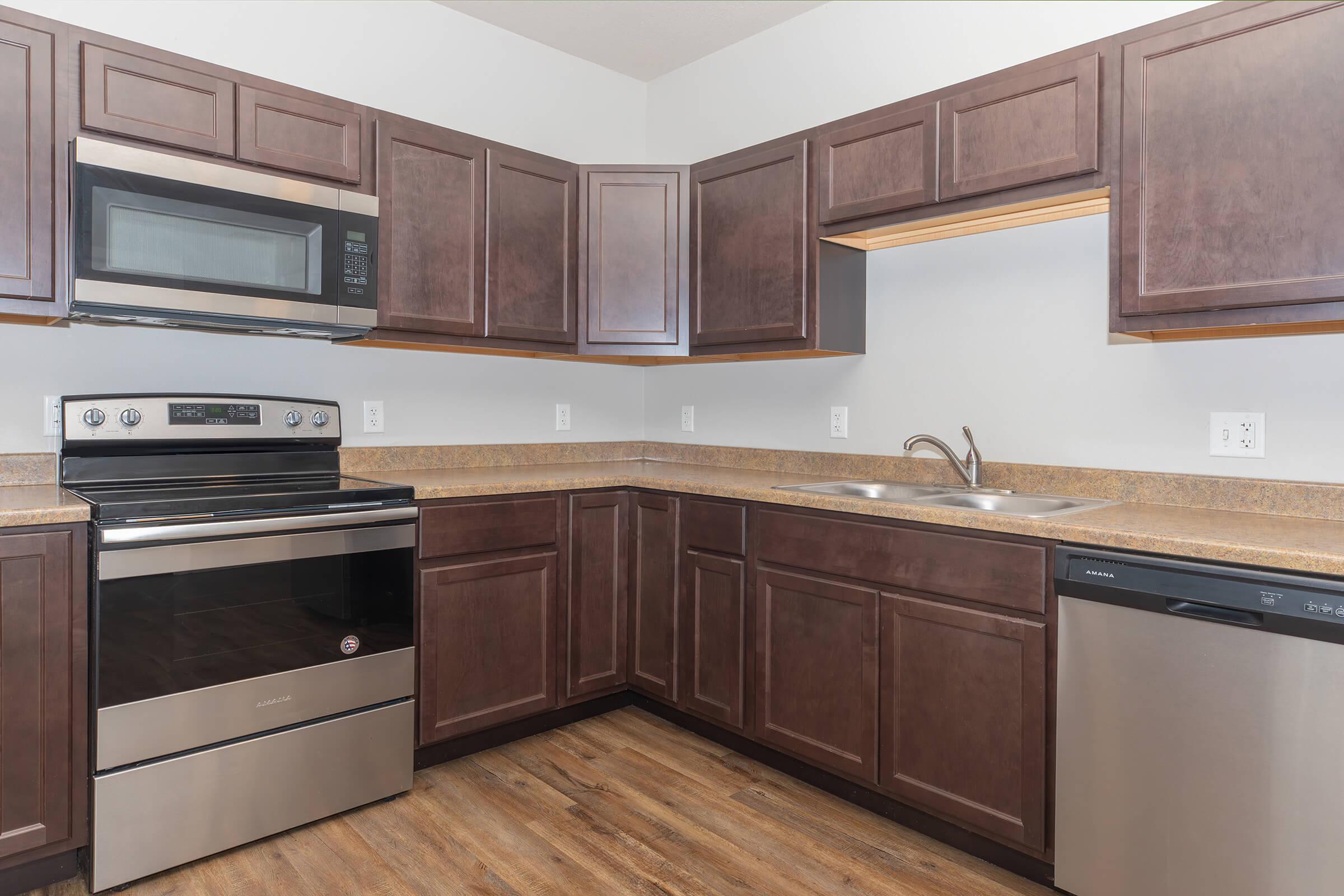 Modern kitchen with stainless steel appliances and dark wood cabinets at The Groves on Devils Glen in Bettendorf, IA