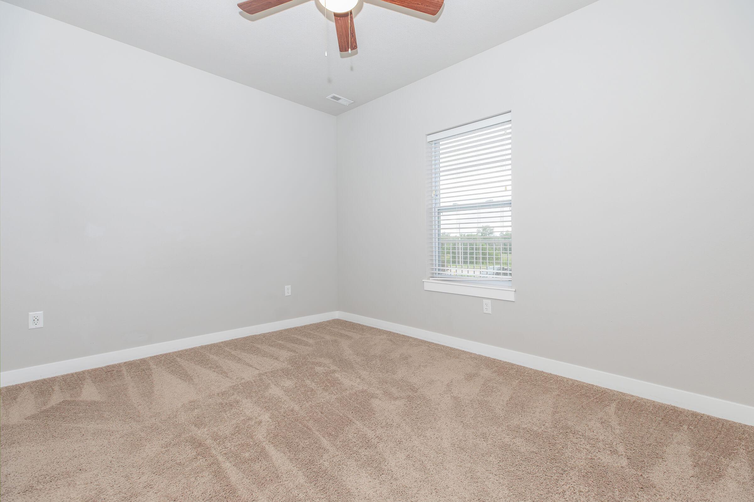 Carpeted bedroom with natural light at The Groves on Devils Glen apartments in Bettendorf, IA