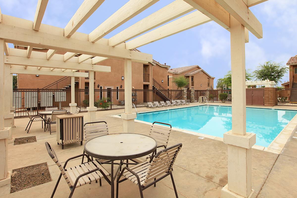 Sonterra Apartment Homes community pool with tables and chairs