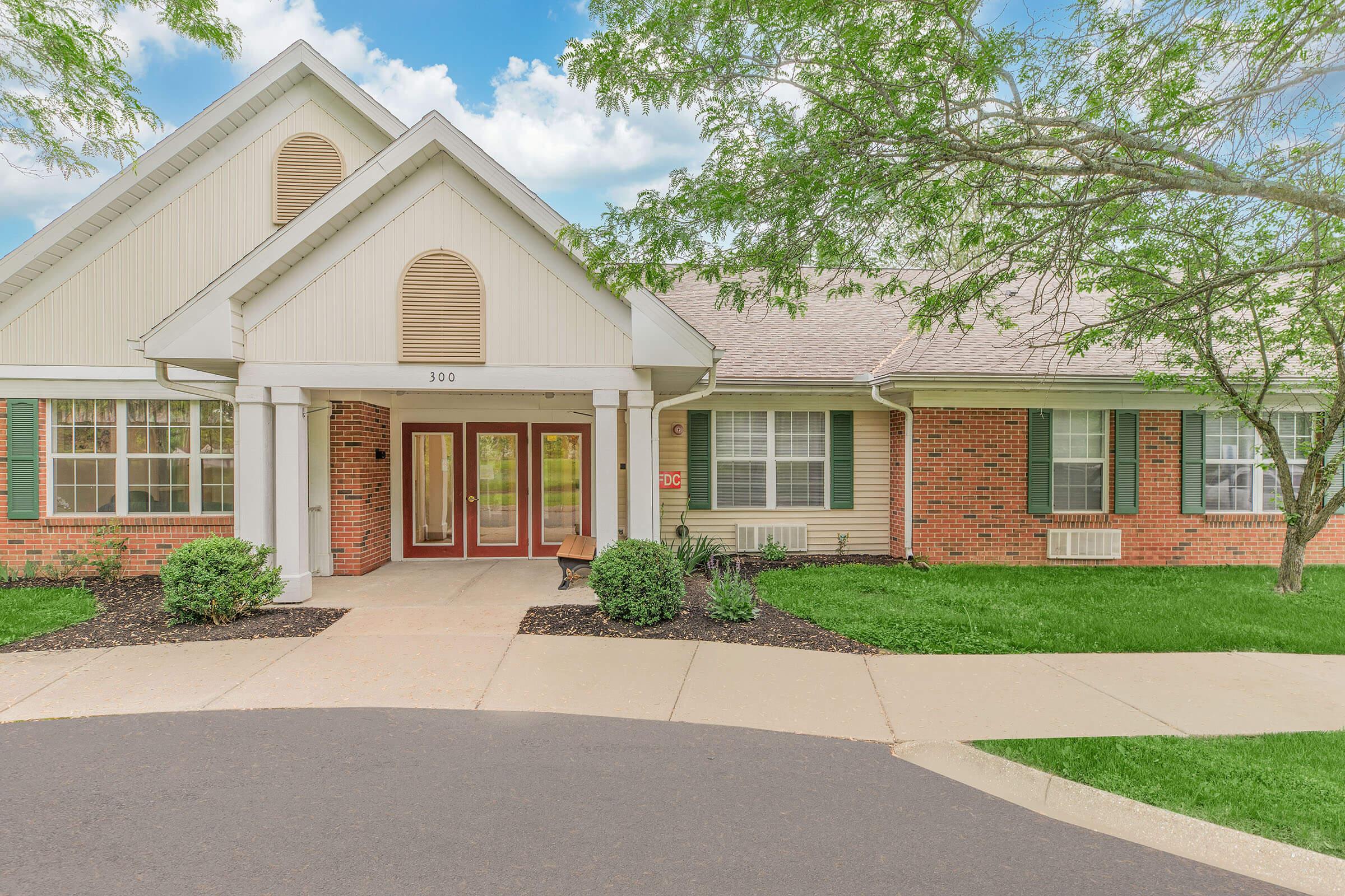 a house with a lawn in front of a brick building