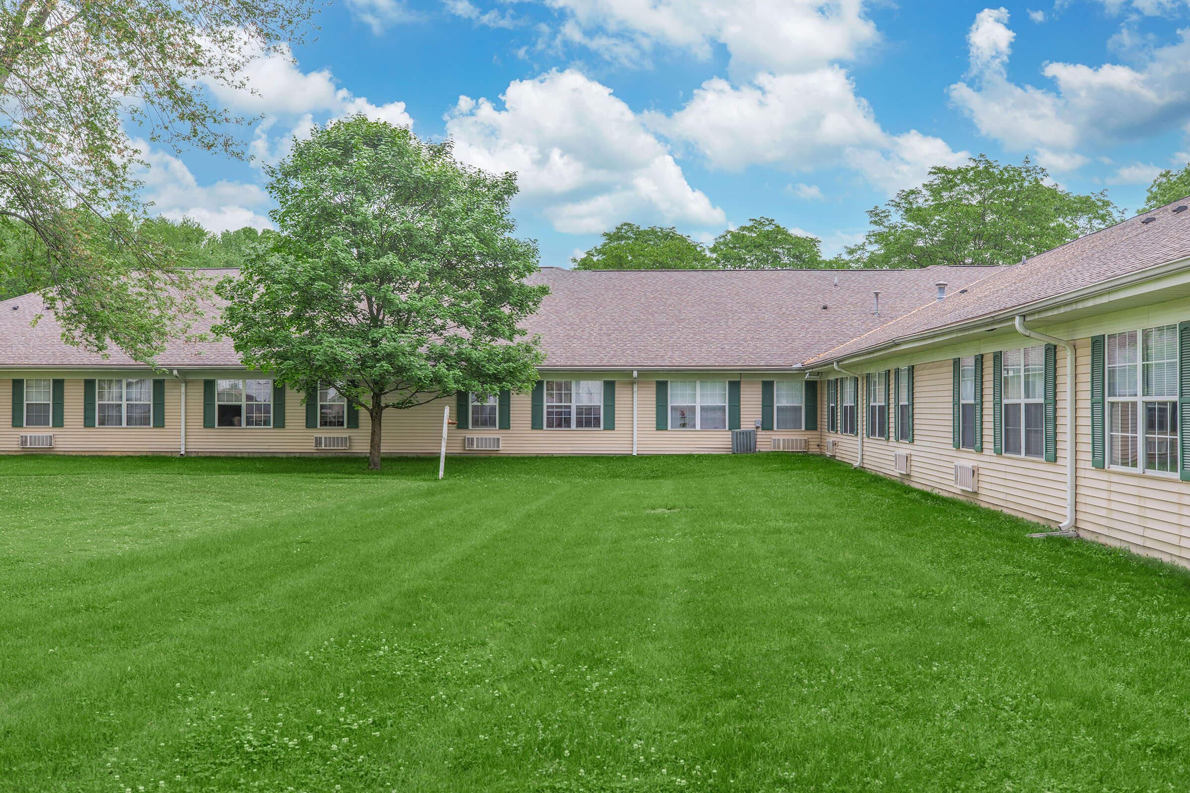 a large brick building with green grass in front of a house