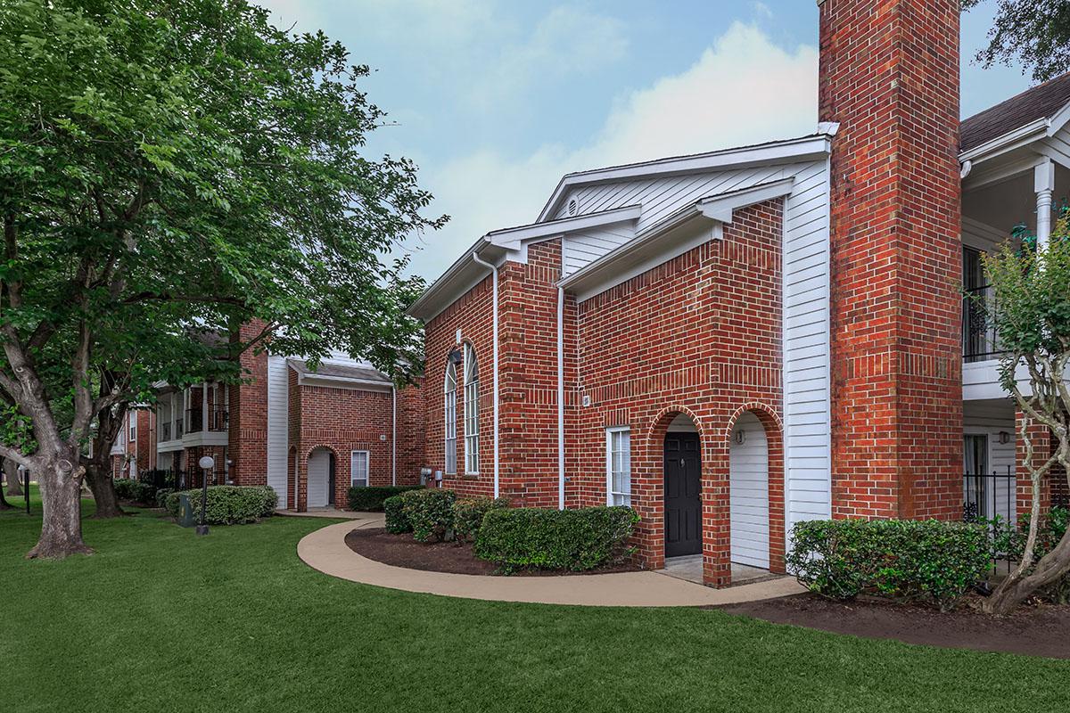 a large brick building with grass in front of a house