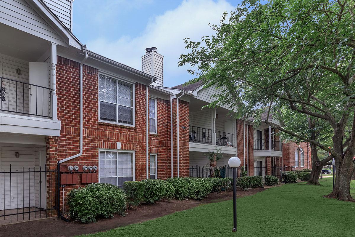 a large brick building with grass in front of a house