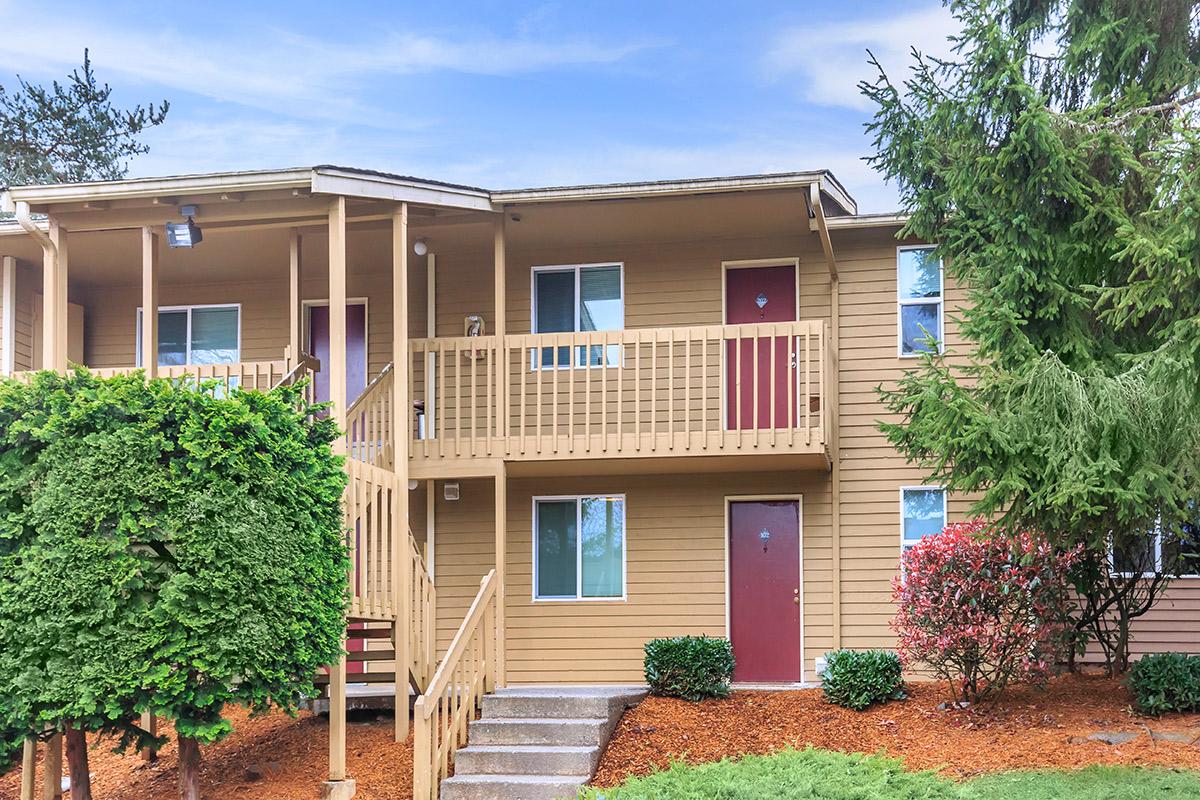 a house with bushes in front of a brick building