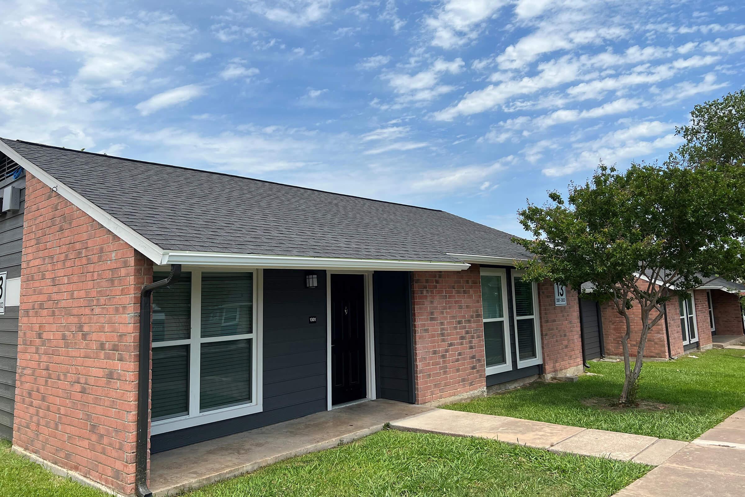 a large brick building with grass in front of a house