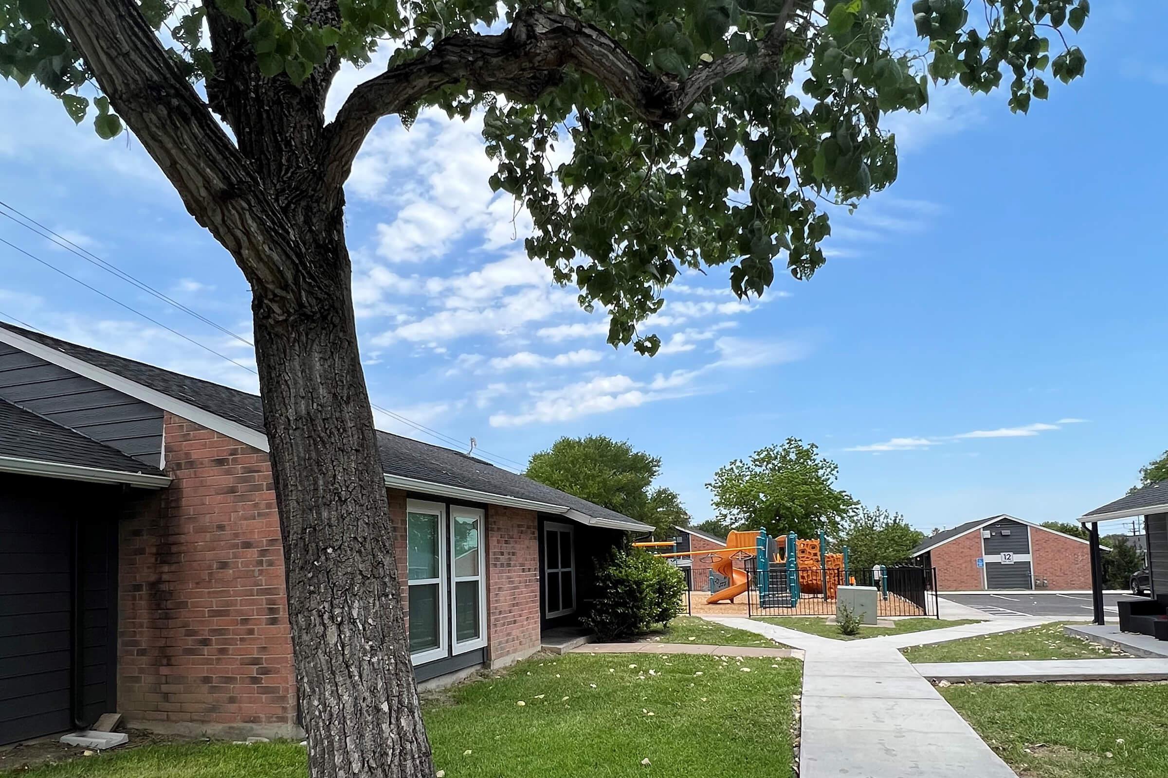 a large brick building with grass in front of a house