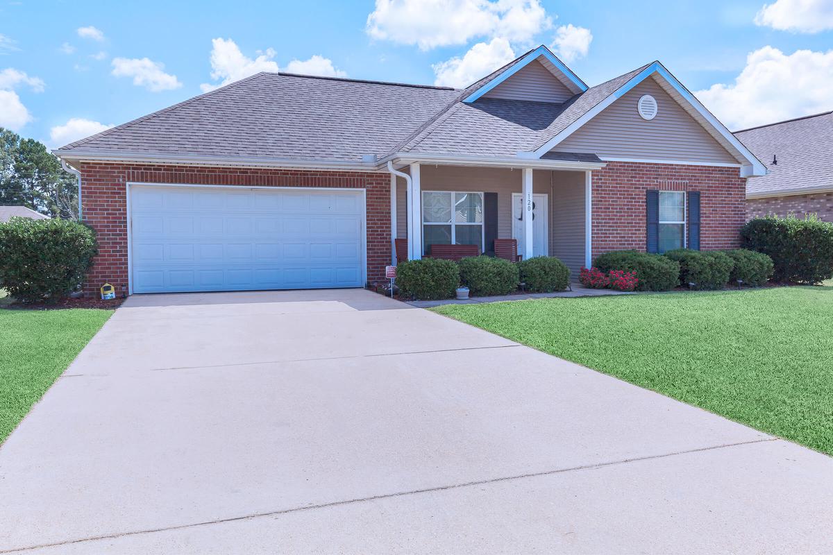 a large brick building with grass in front of a house