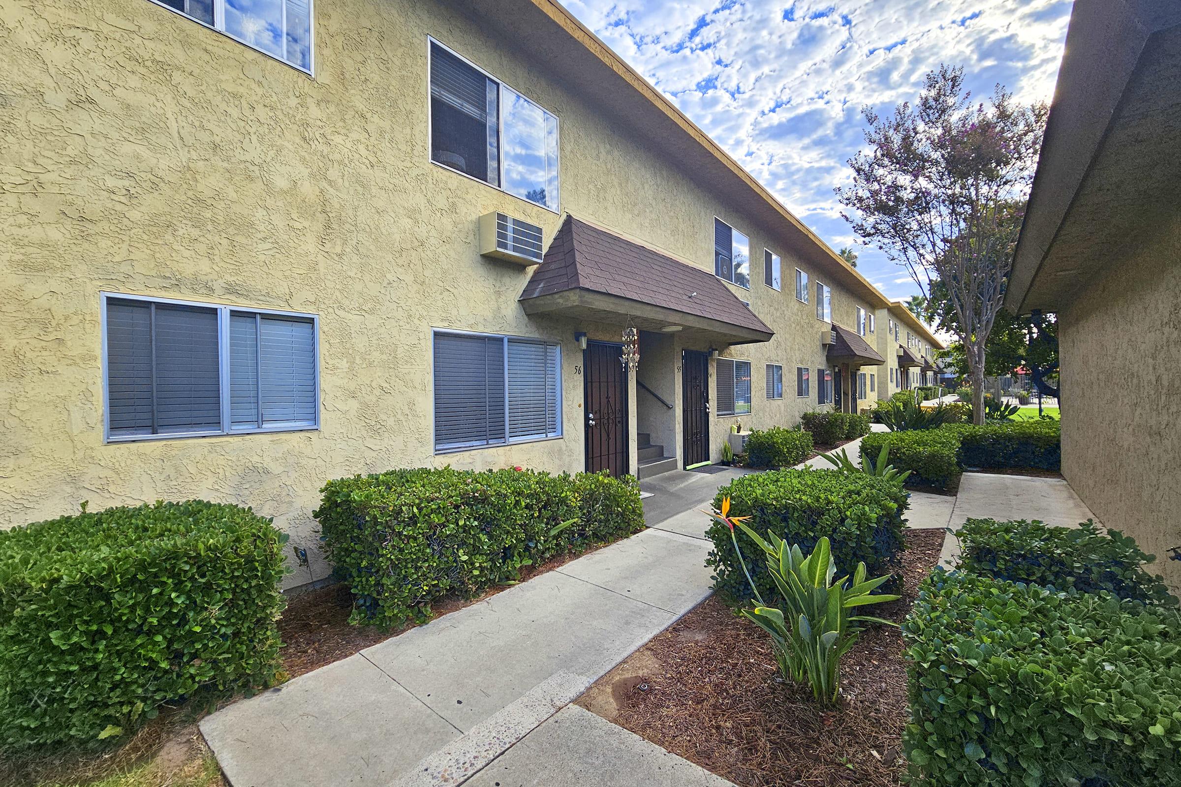 a house with bushes in front of a brick building