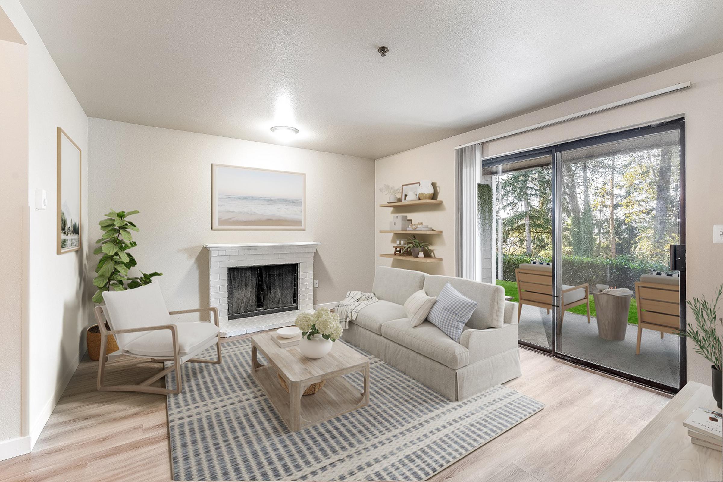 Bright and airy living room featuring a light-colored sofa with soft cushions, a wooden coffee table, and a decorative area rug. A fireplace is in the foreground, with plants and shelves displaying decorative items. Large sliding glass doors open to a patio with views of greenery. Natural light fills the space.