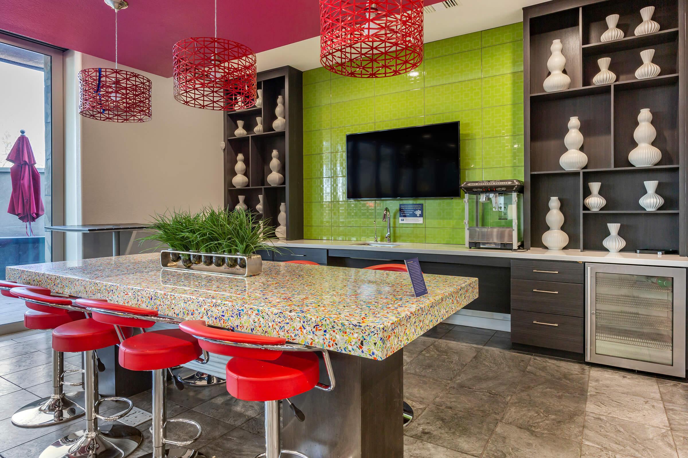 Modern kitchen area featuring a vibrant mosaic countertop with red bar stools.