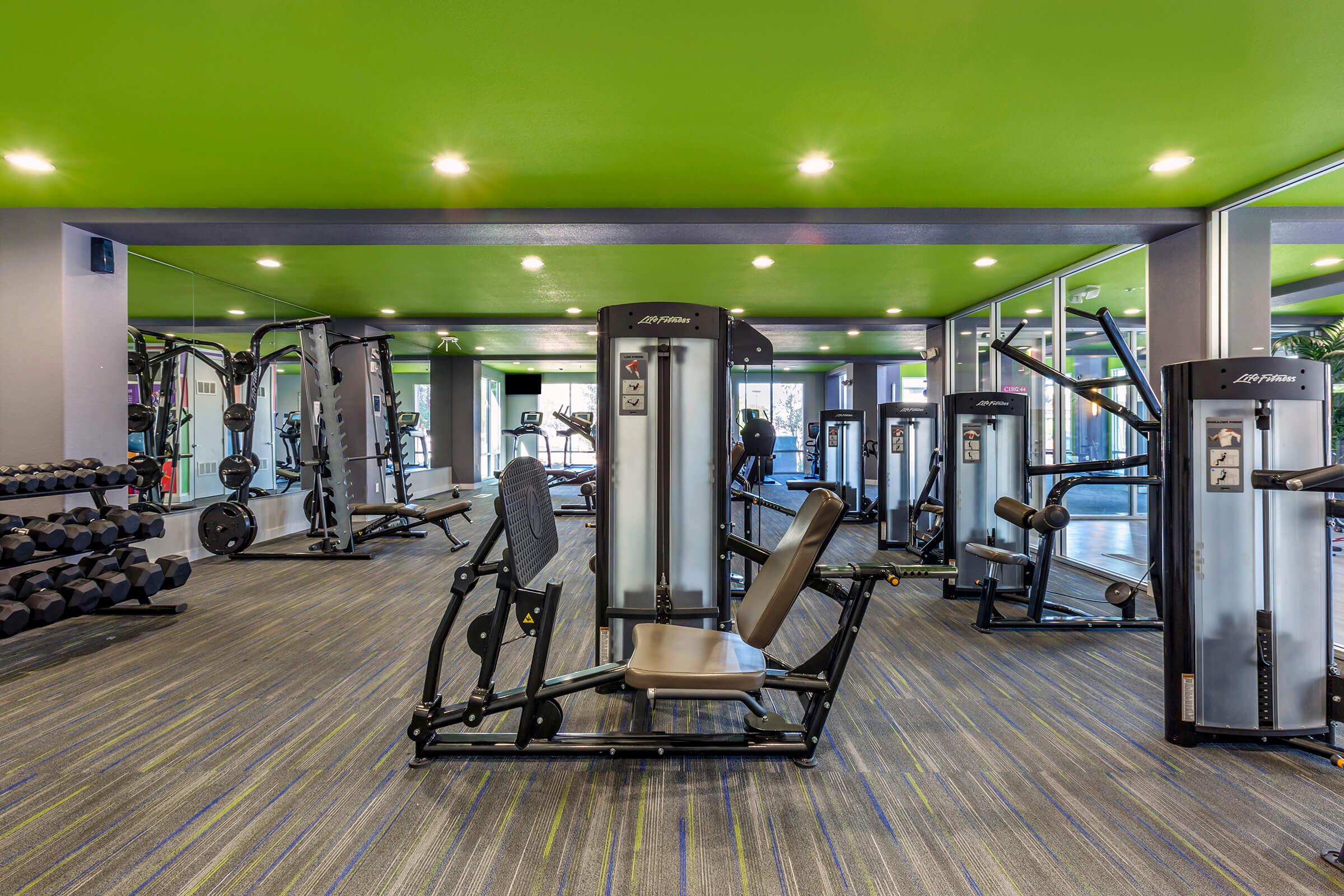A modern gym interior featuring various fitness equipment, including weight machines, dumbbells, and cardio machines.