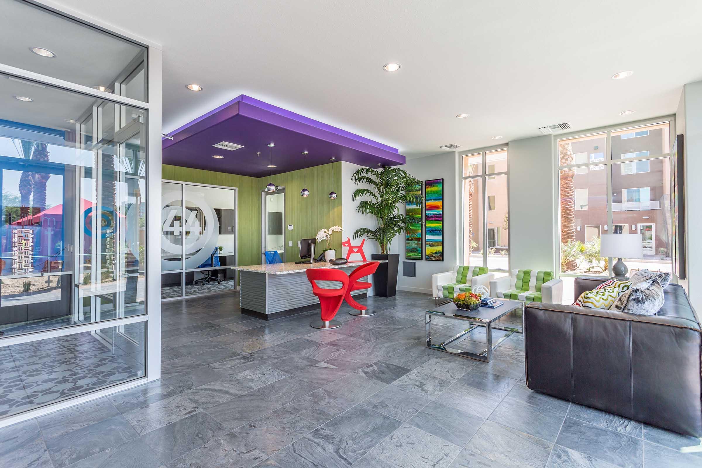 Modern reception area with sleek design featuring a unique purple ceiling, contemporary furniture, and large windows allowing natural light.