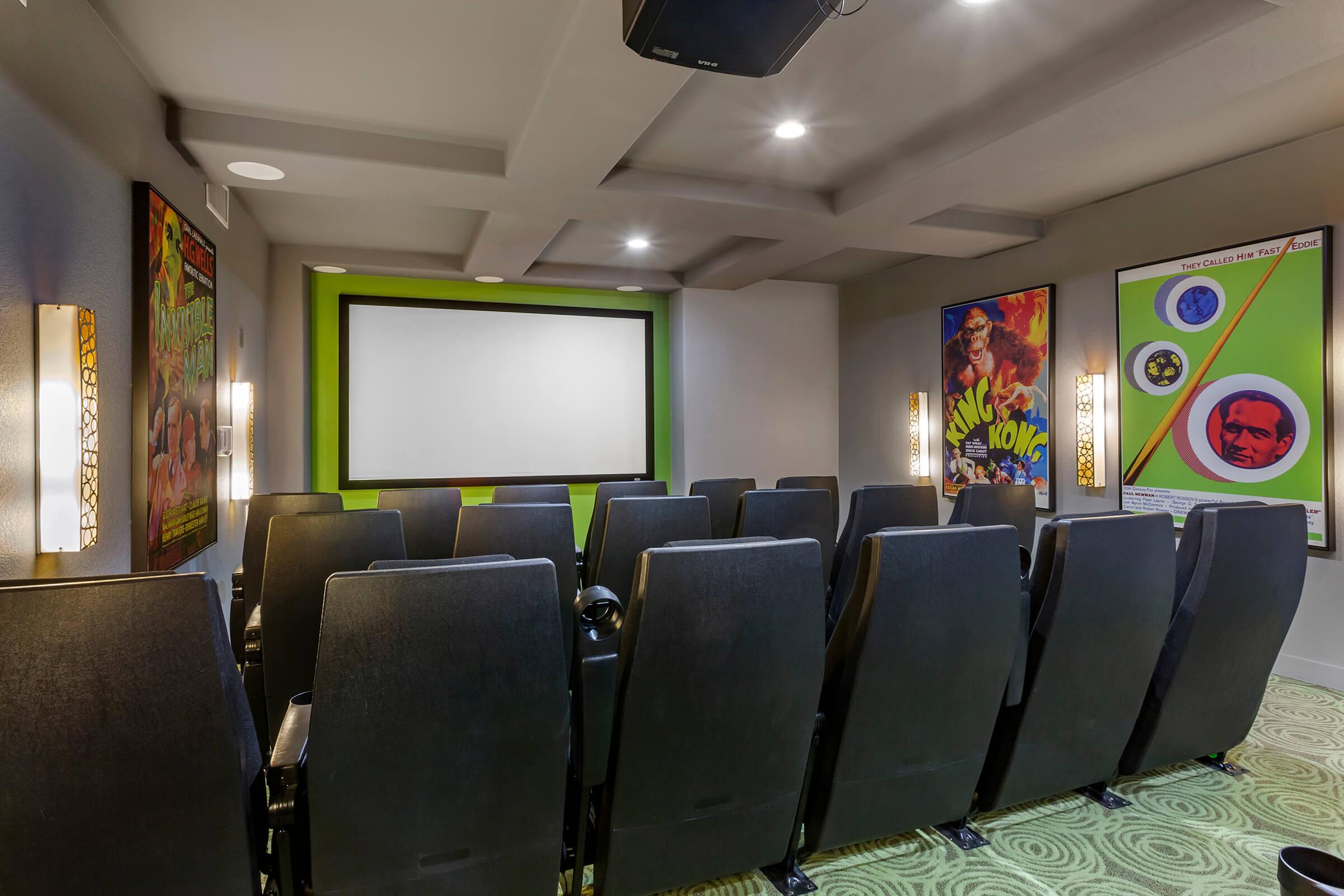 A cozy home theater featuring a large screen at the front and rows of black seating.