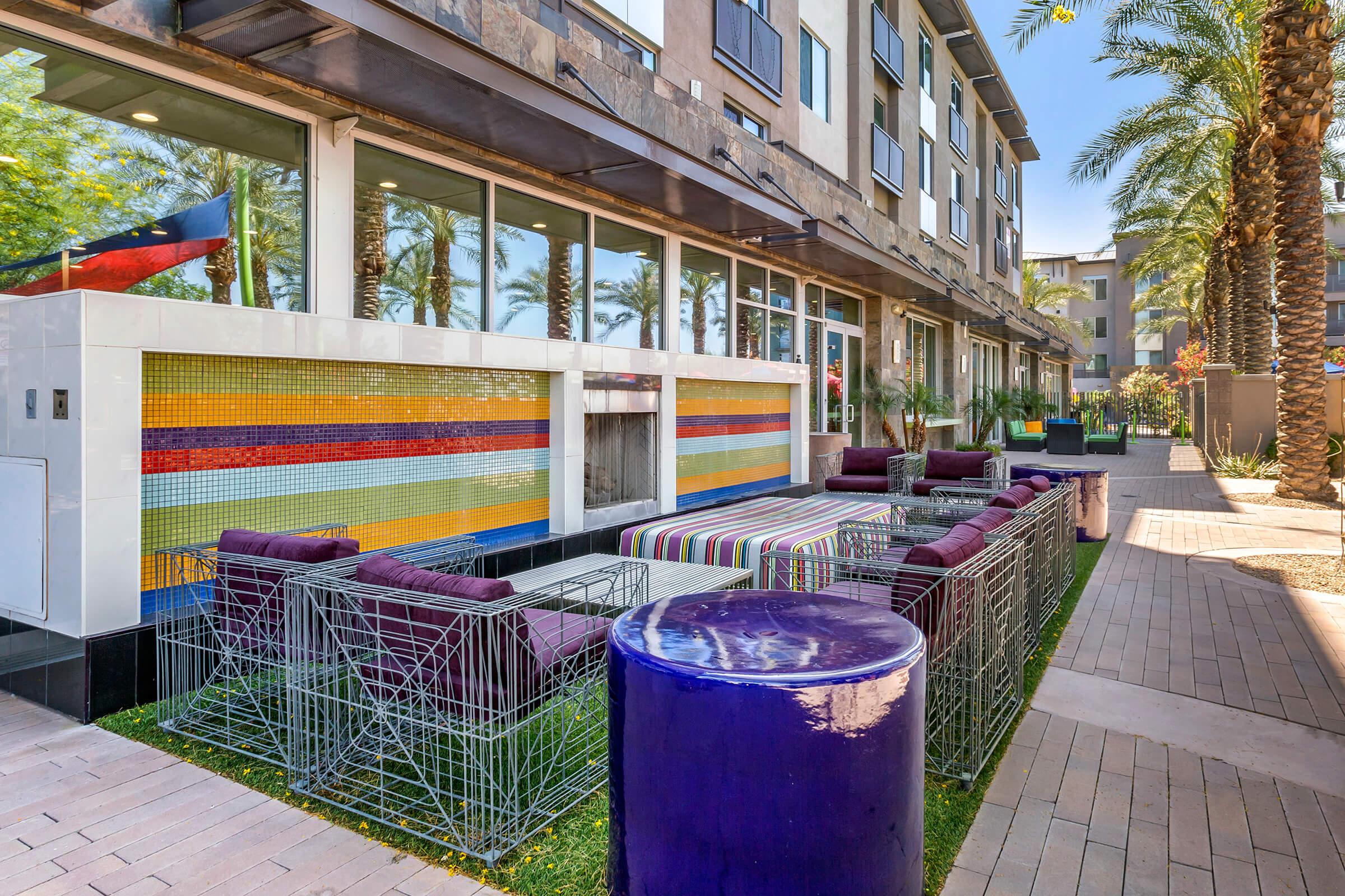 Outdoor seating area featuring colorful lounge furniture, modern design elements, and palm trees.