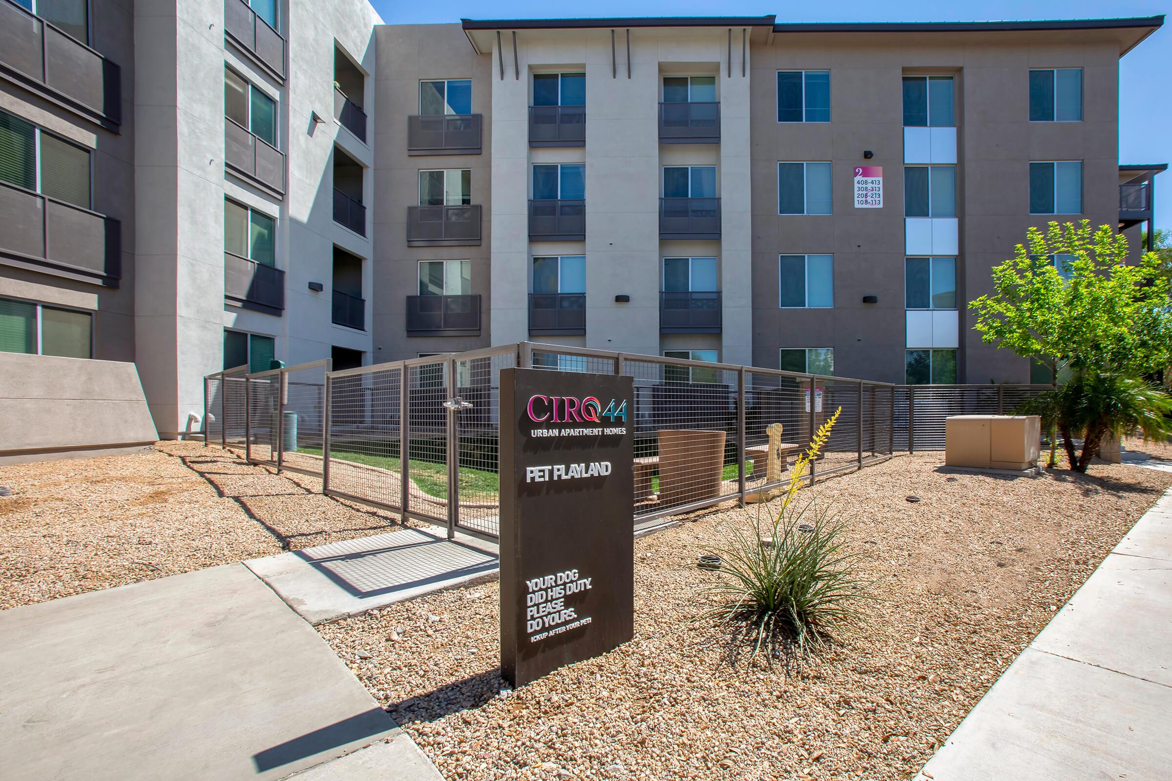 A view of a modern apartment complex featuring a fenced pet area.