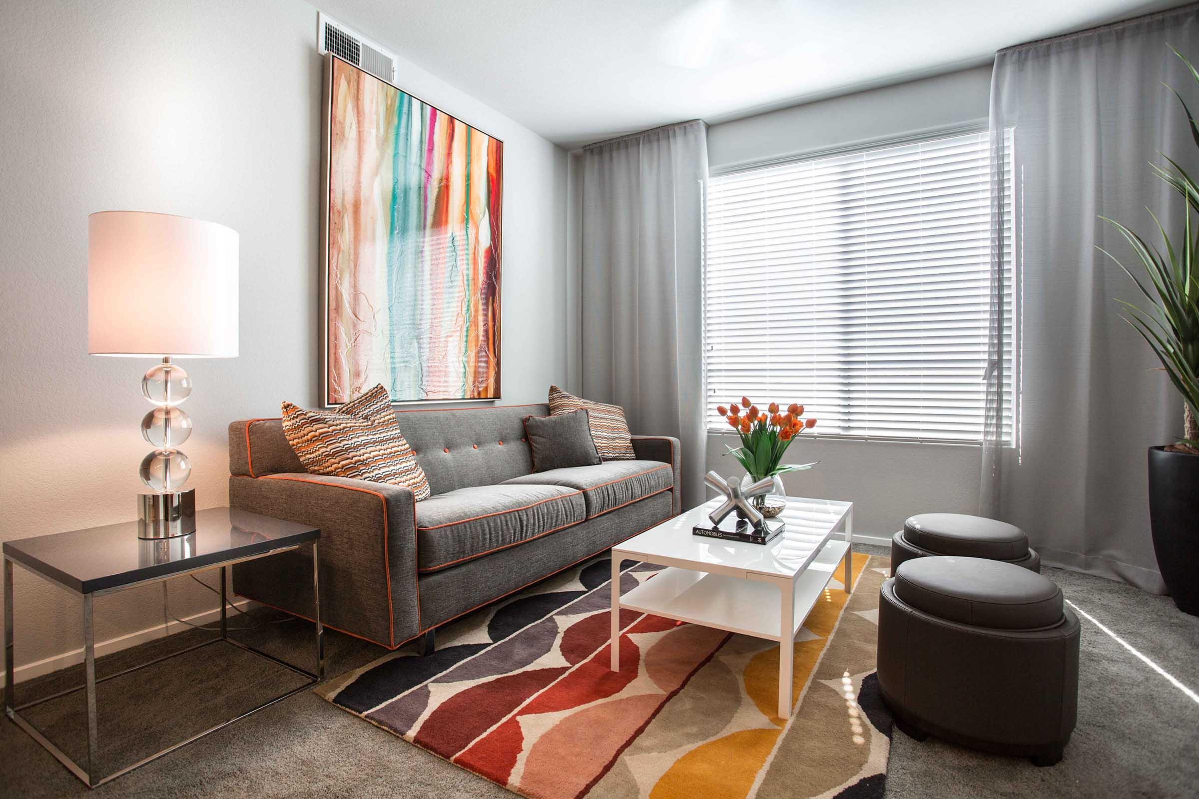 A cozy living room featuring a gray sofa with colorful cushions, a modern glass lamp, and a stylish coffee table.