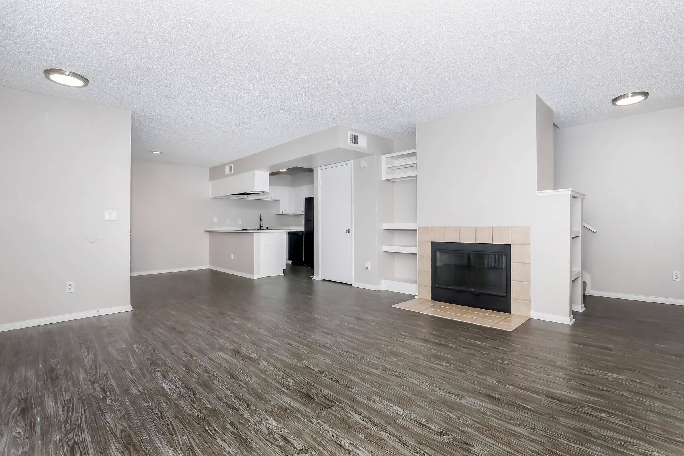 Apartments for Rent in Corona, CA - The Hills of Corona - Living Room with a Fireplace, Built-In Shelves, and Hardwood-Style Flooring