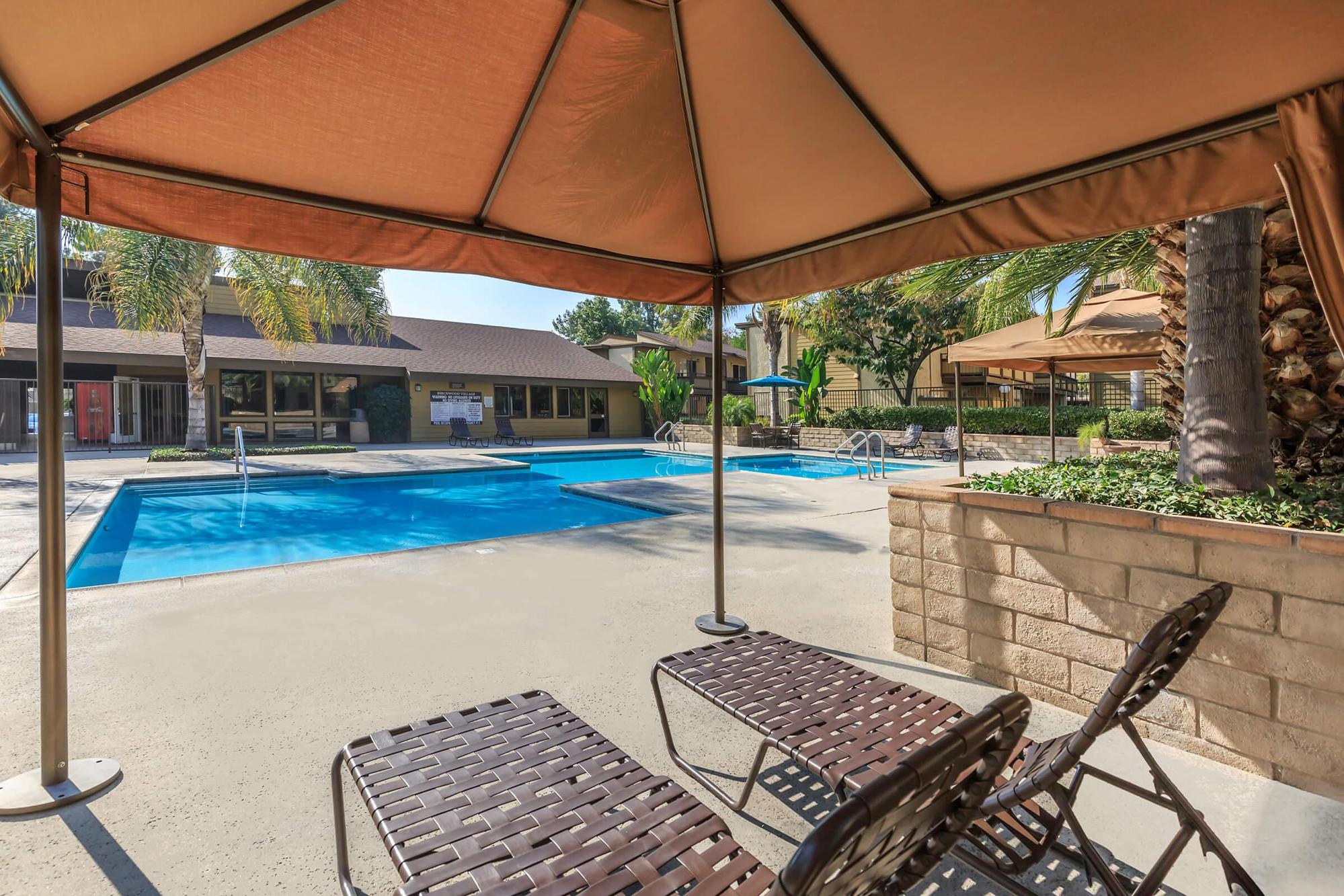 Birchwood Village Apartments community pool with chairs under a cabana