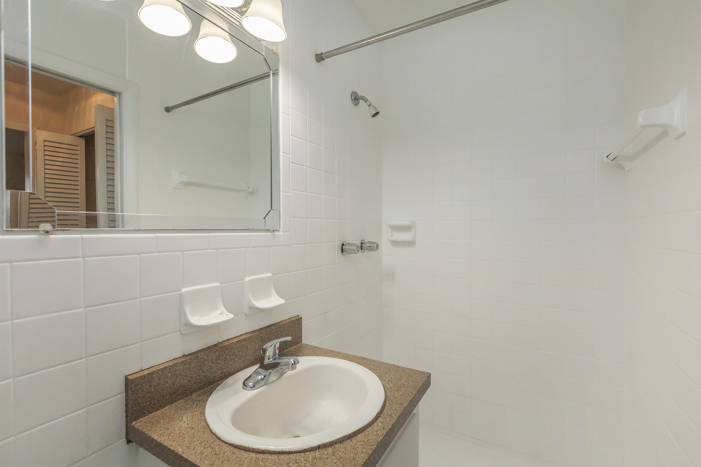 a white sink sitting under a mirror