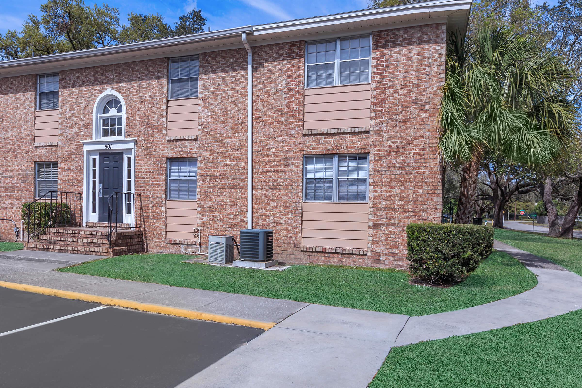 a large brick building with grass in front of a house