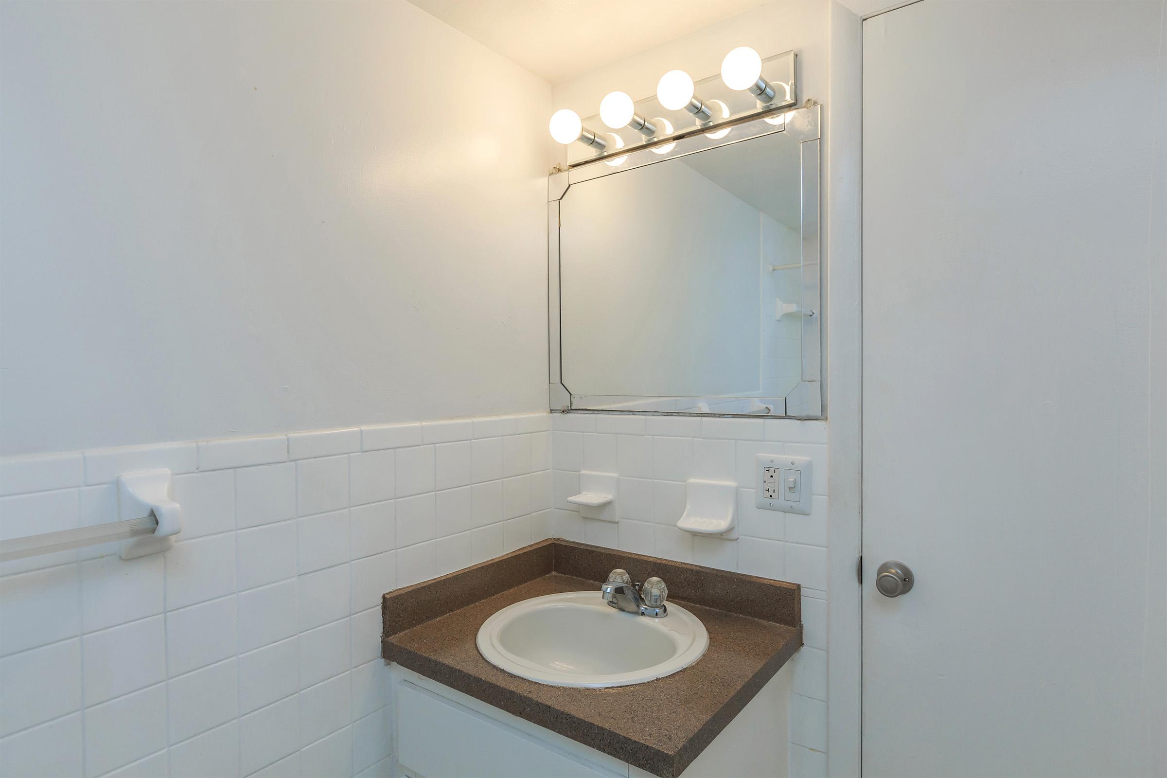 a white sink sitting under a mirror