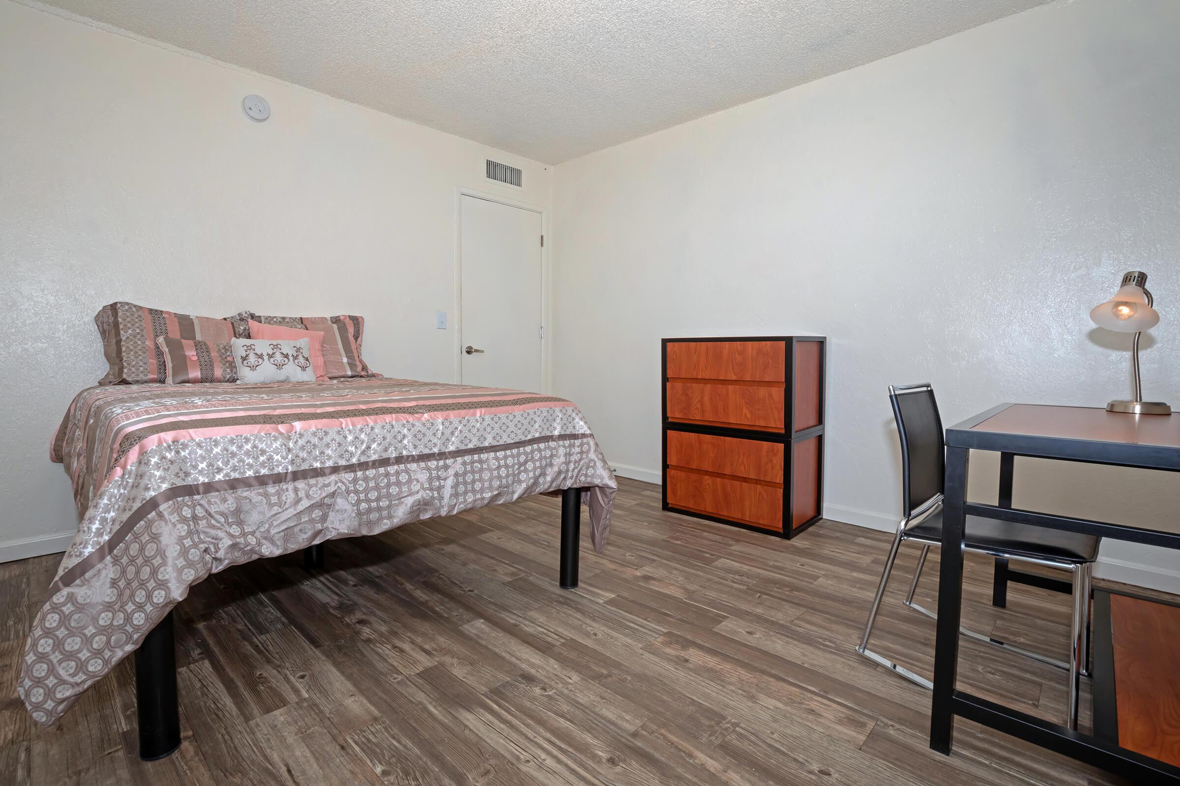 a bedroom with a bed and desk in a room