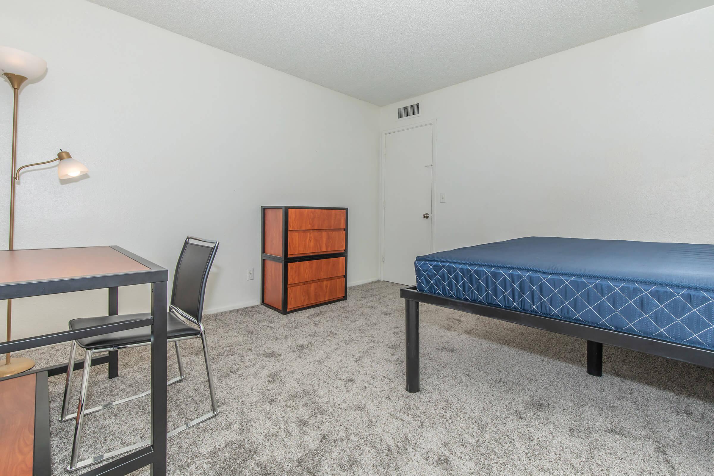 a bedroom with a bed and desk in a room