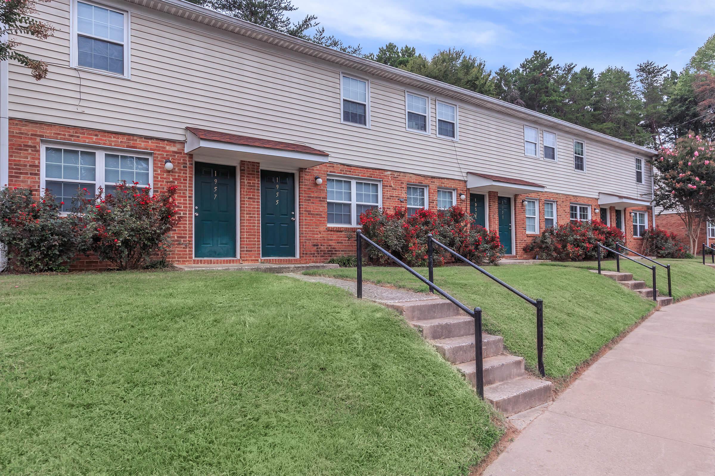 a large brick building with grass in front of a house