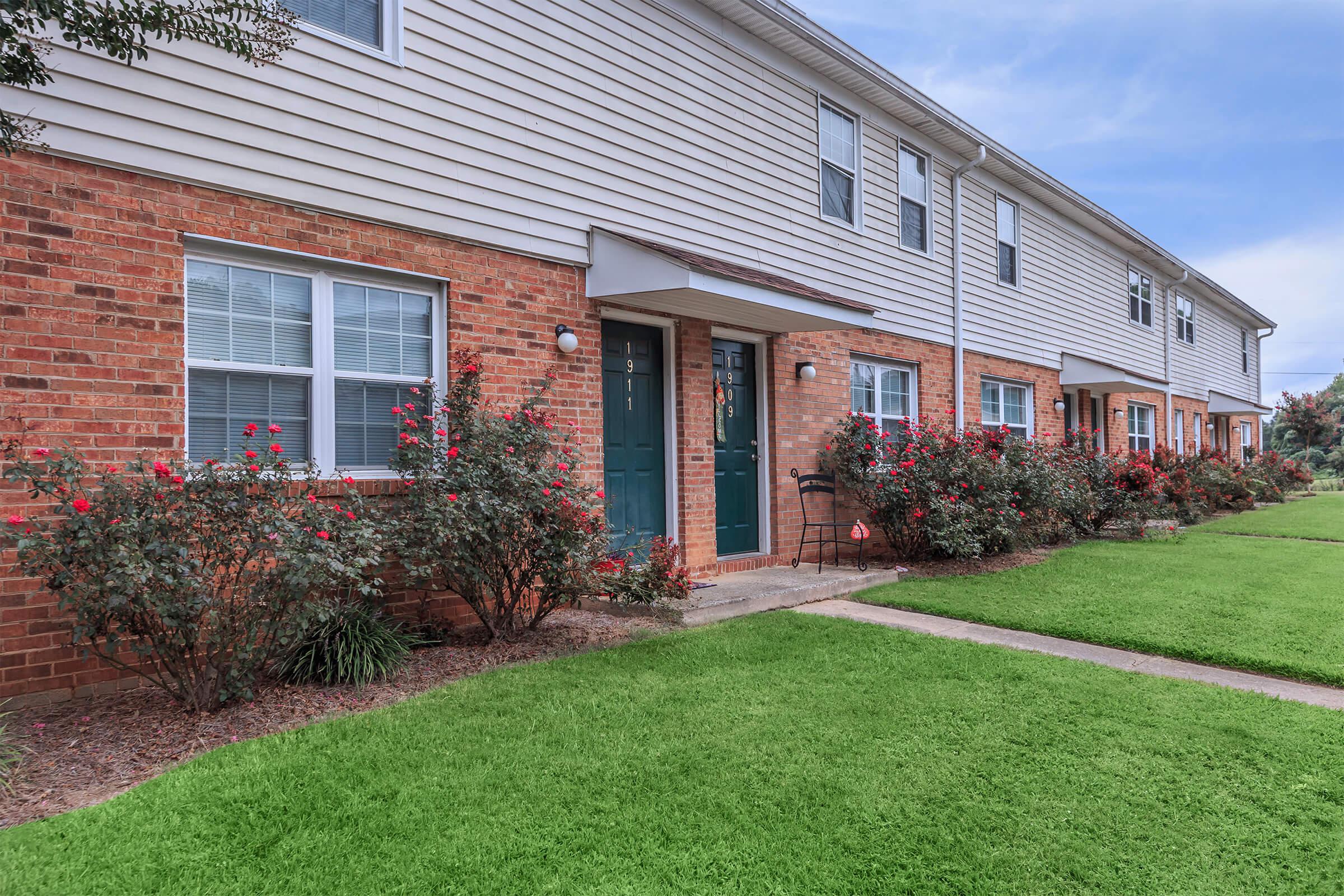 a large brick building with grass in front of a house