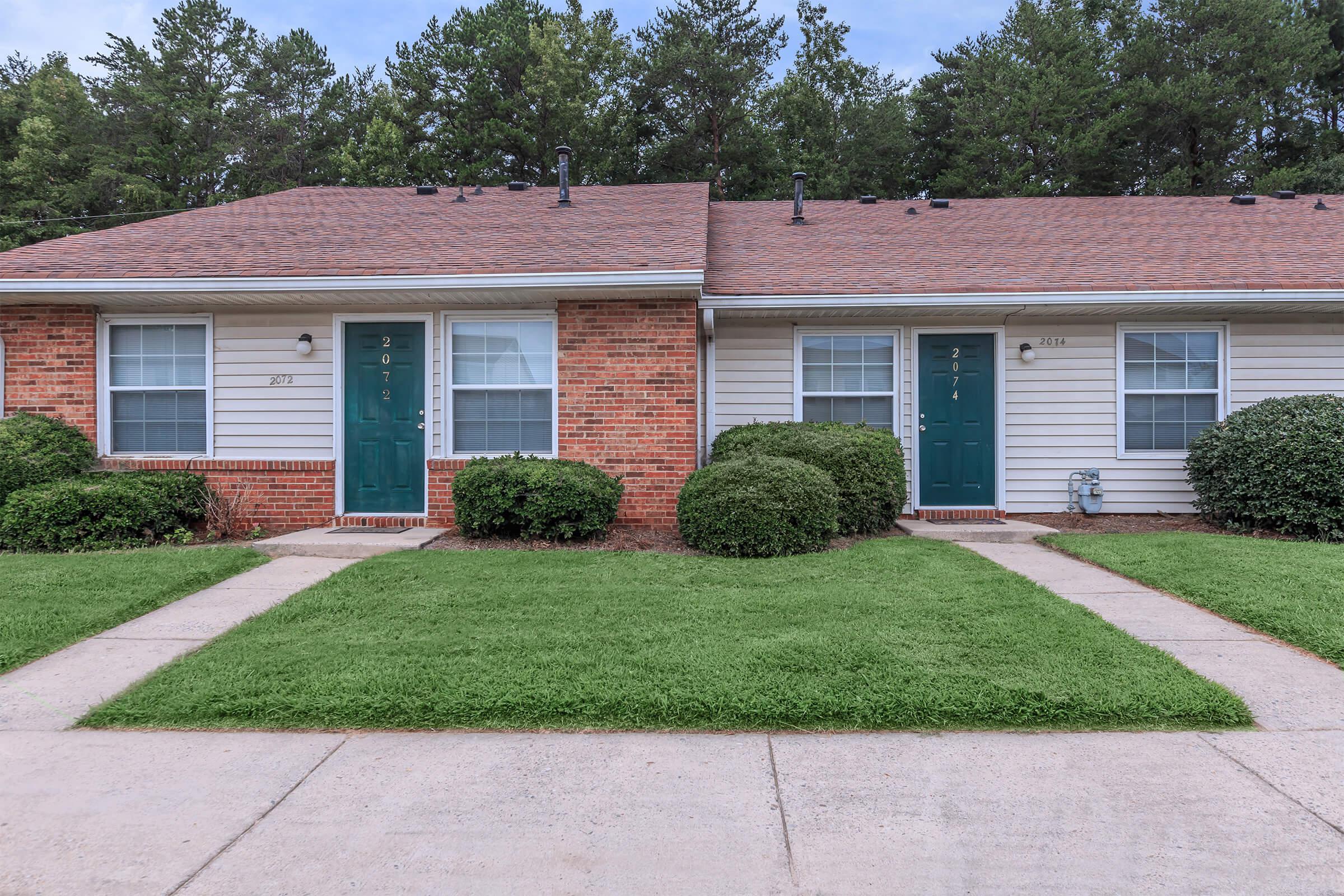 a large brick building with grass in front of a house