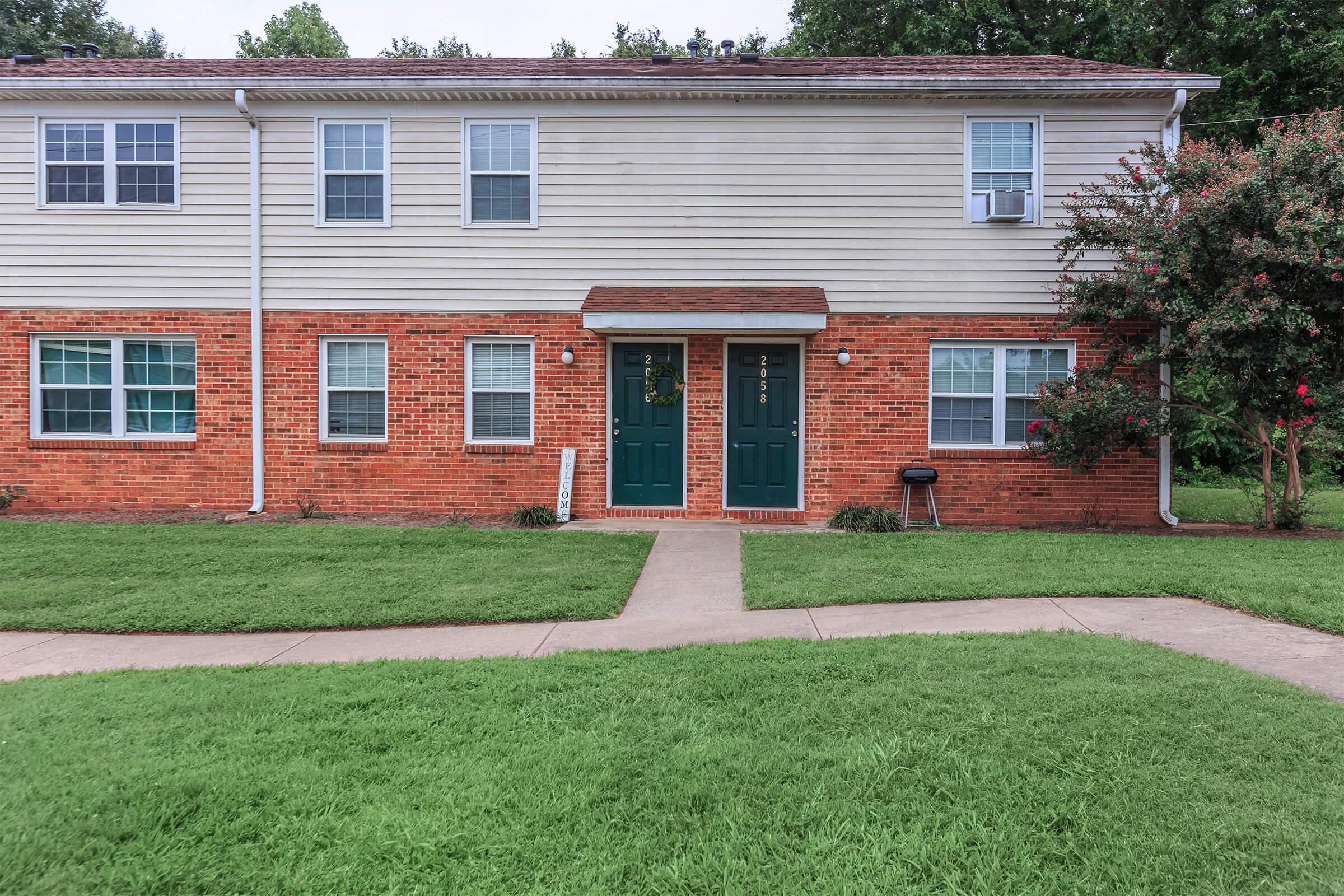 a large brick building with grass in front of a house