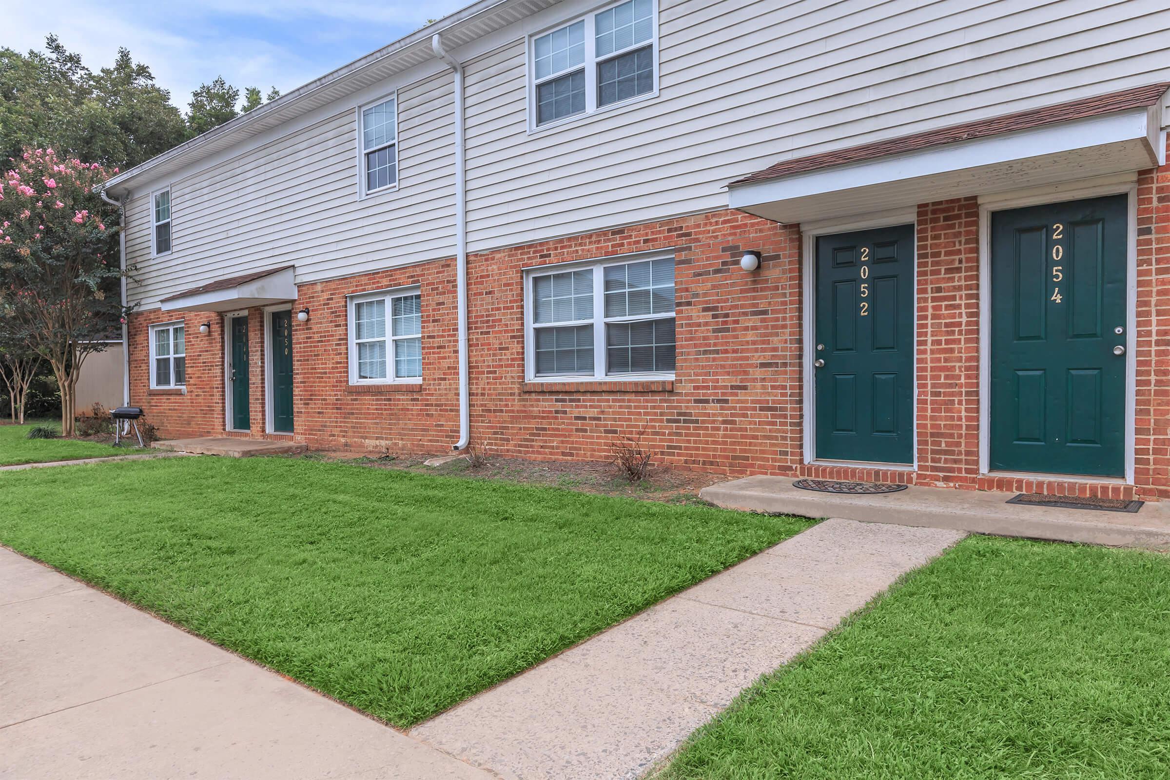 a house with a lawn in front of a brick building