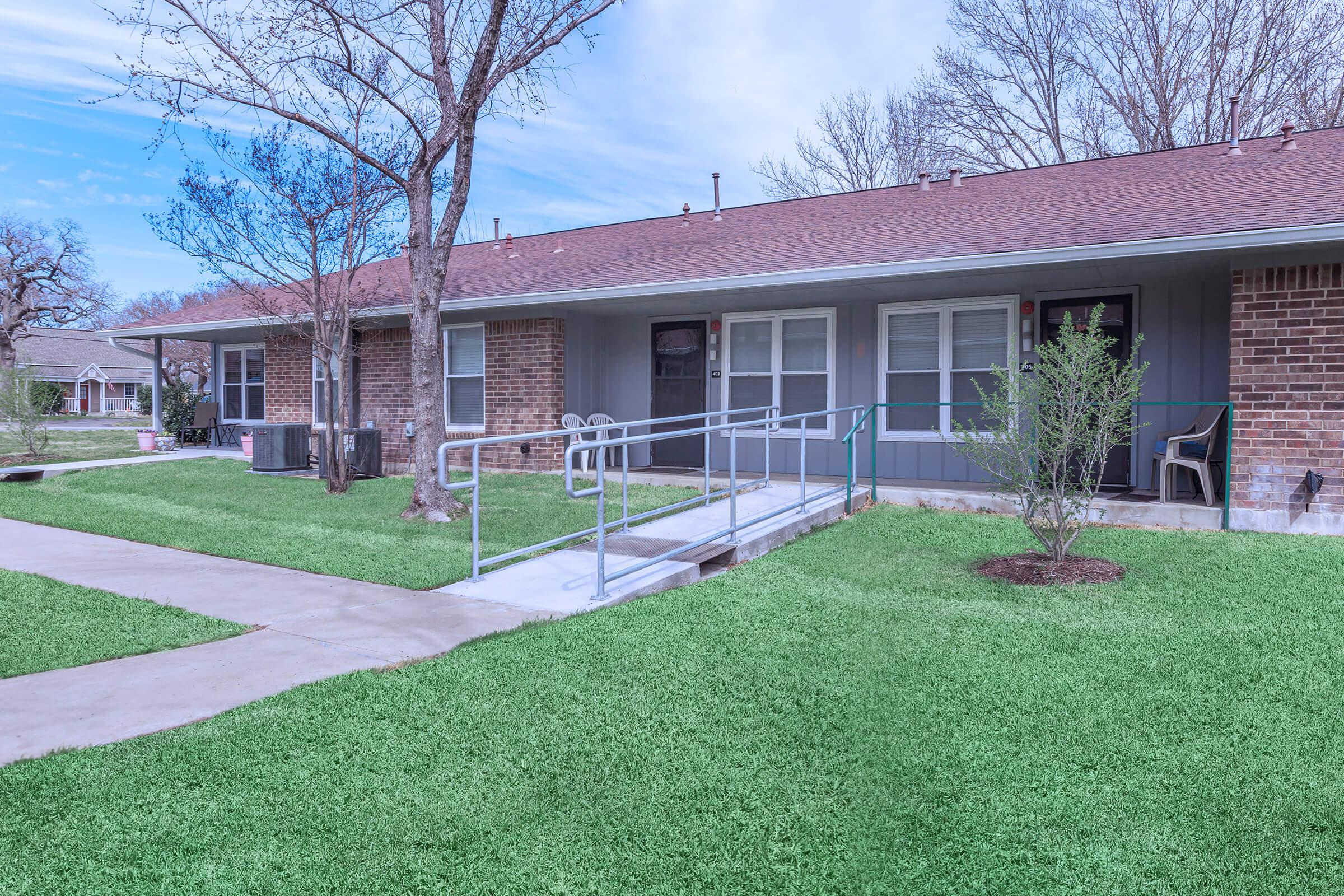 a house with a lawn in front of a brick building