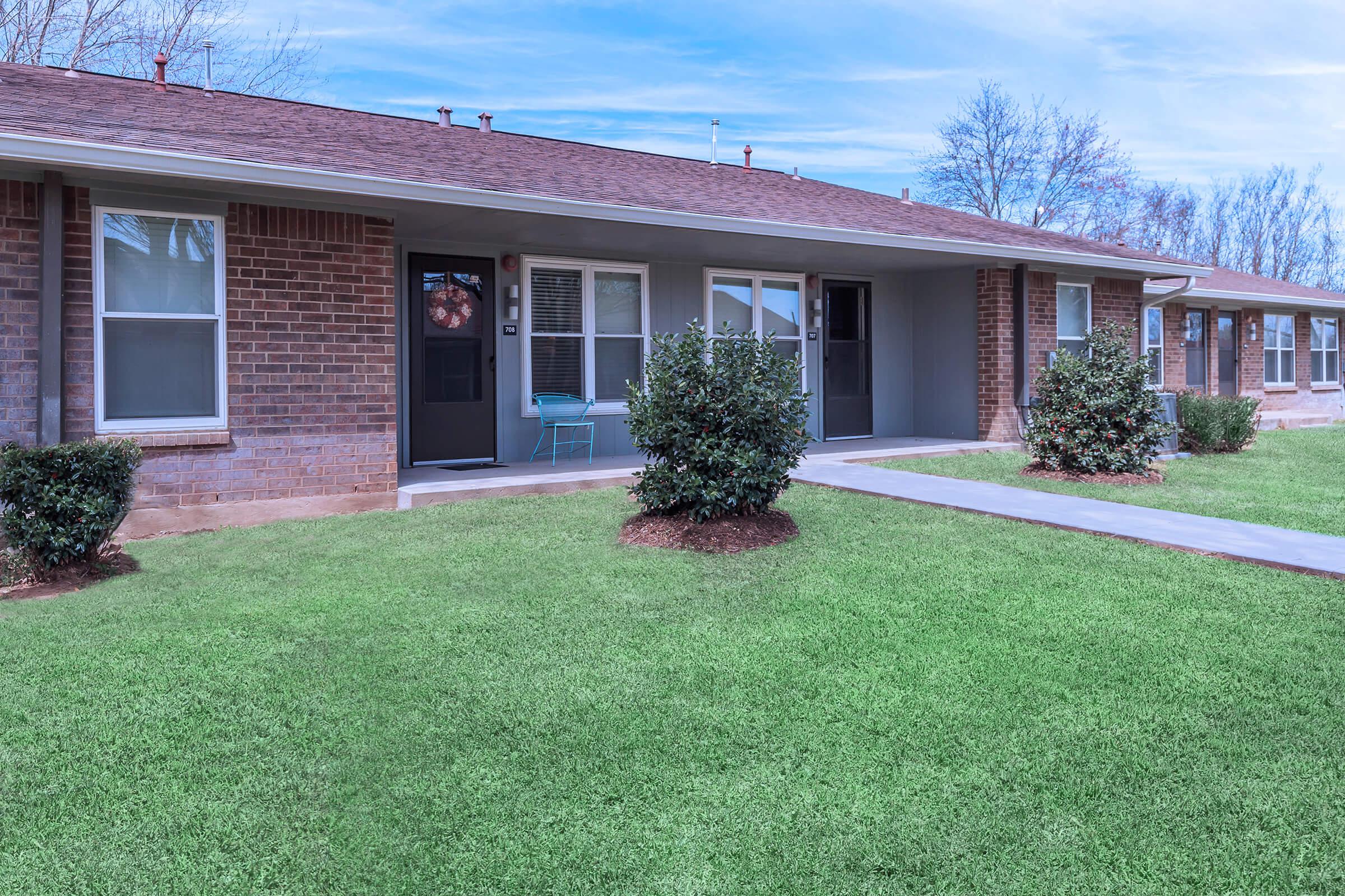 a house with a lawn in front of a brick building