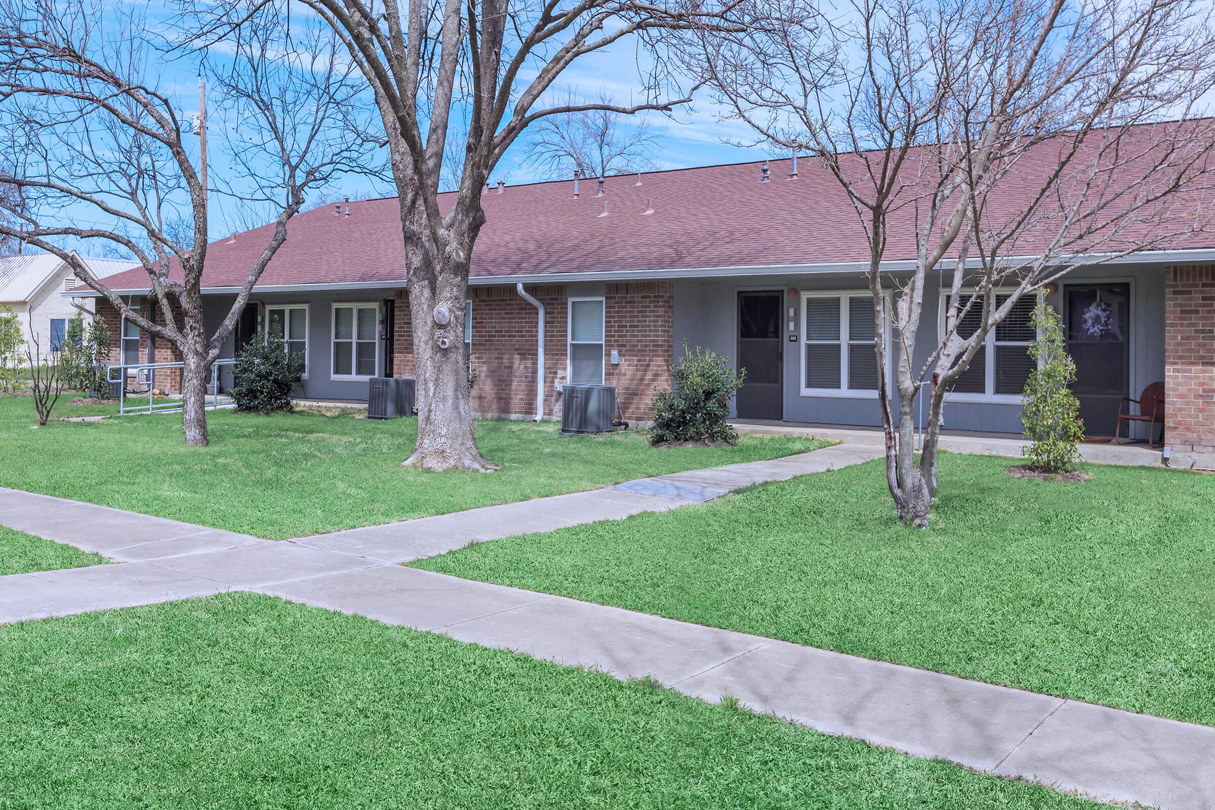 a house with a lawn in front of a brick building