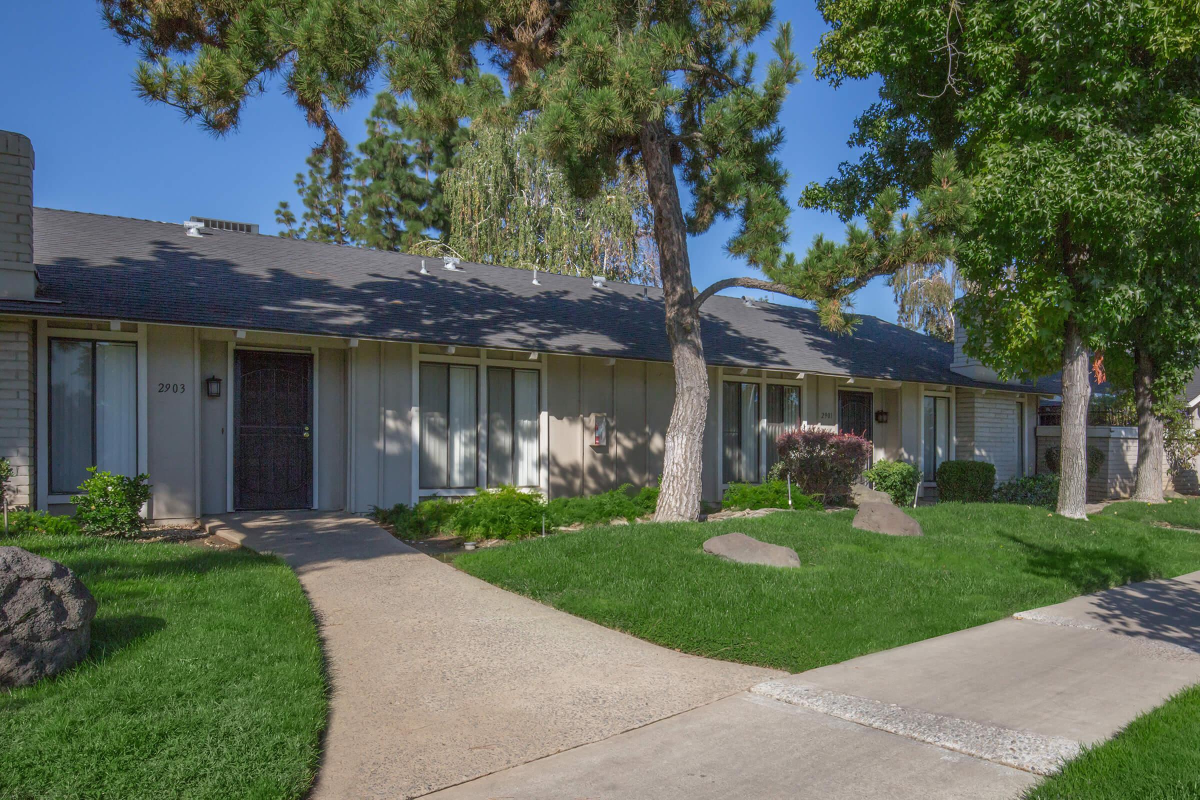 a house with a lawn in front of a brick building