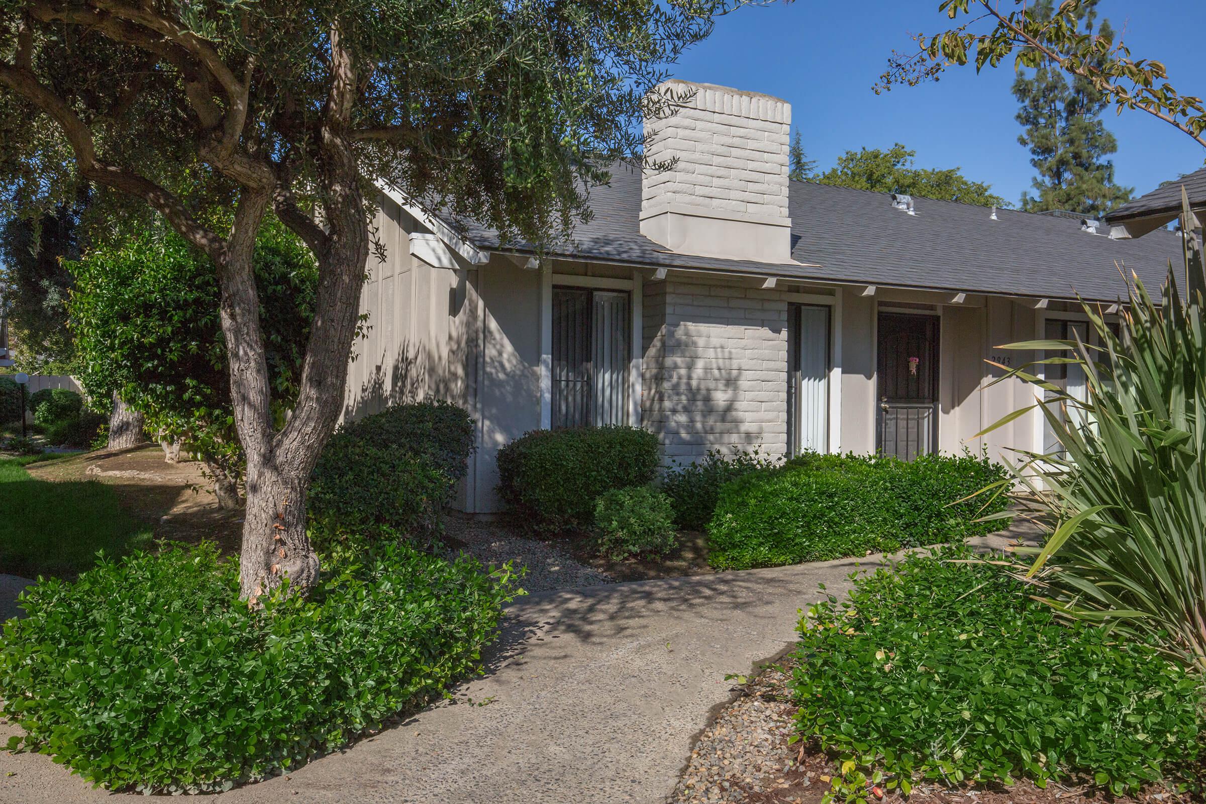 a house with bushes in front of a brick building