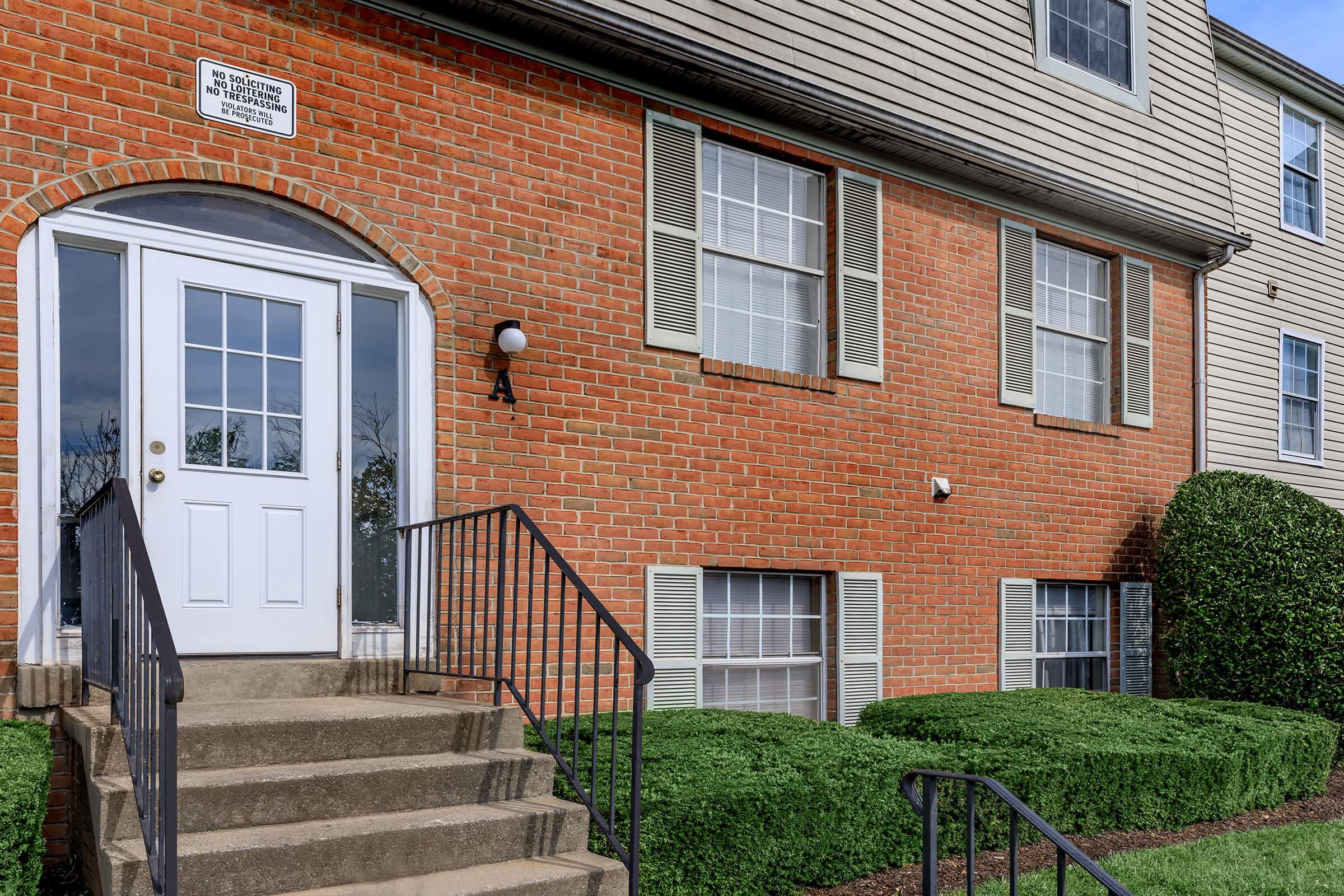 a large brick building with grass in front of a house