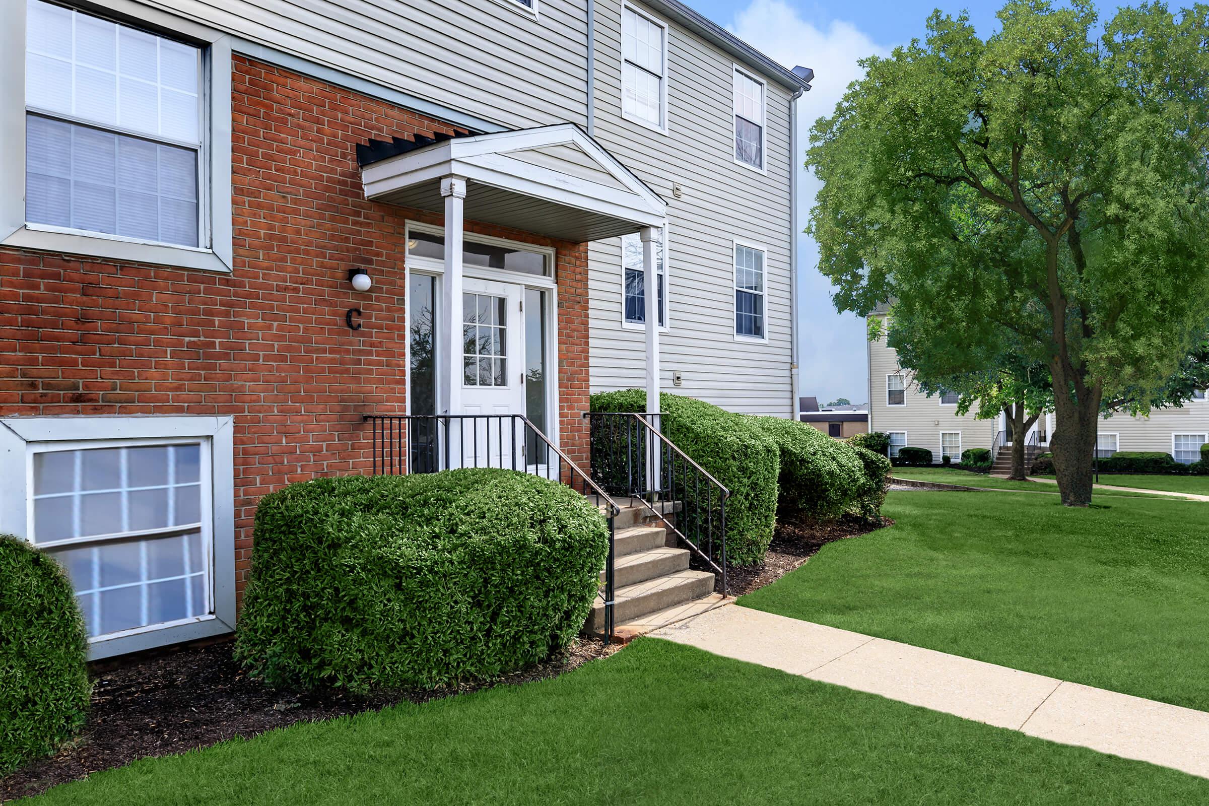 a house with a lawn in front of a brick building