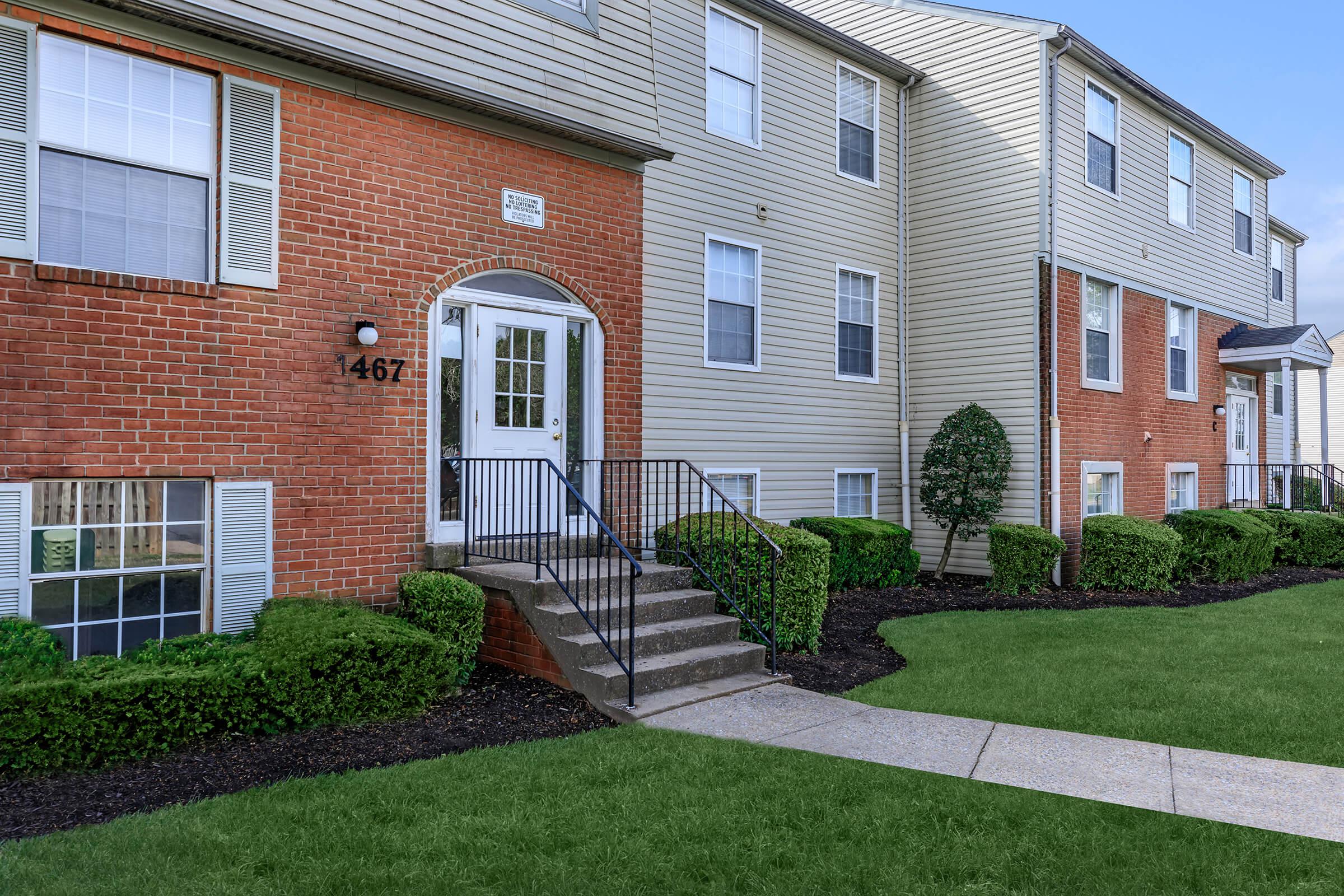 a large brick building with grass in front of a house