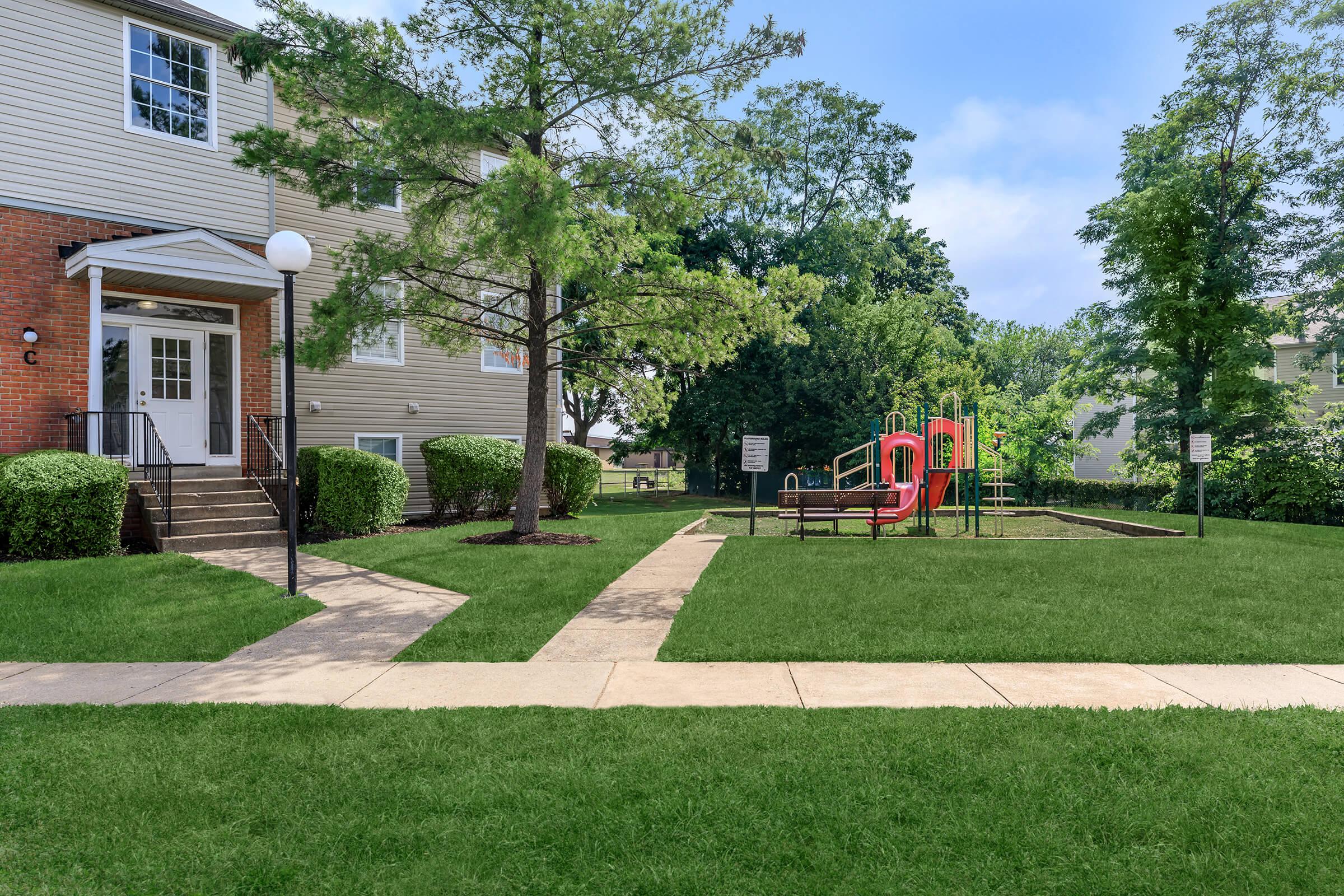 a large brick building with grass in front of a house