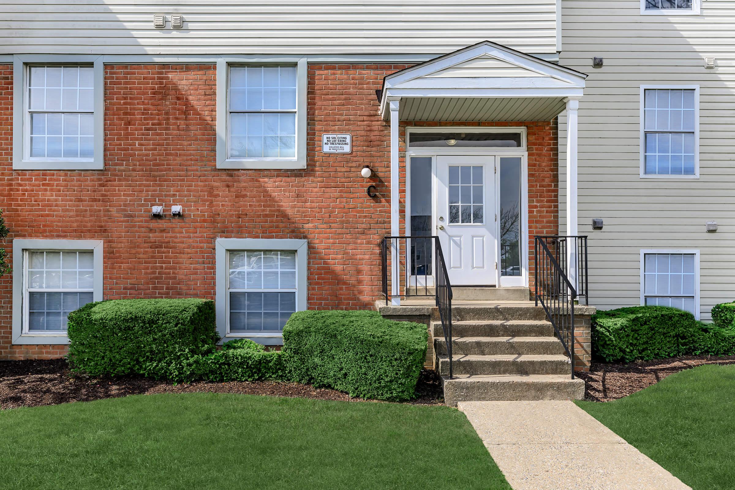 a house with a lawn in front of a brick building