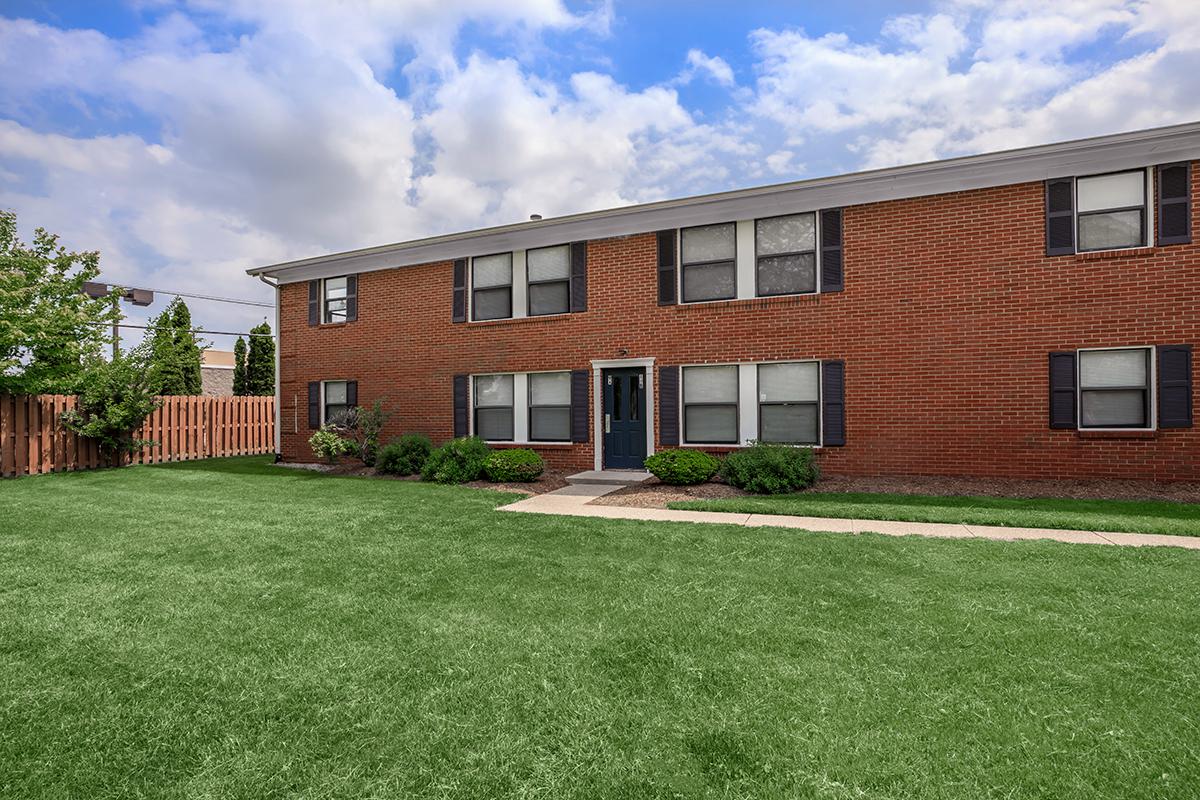 a large brick building with grass in front of a house