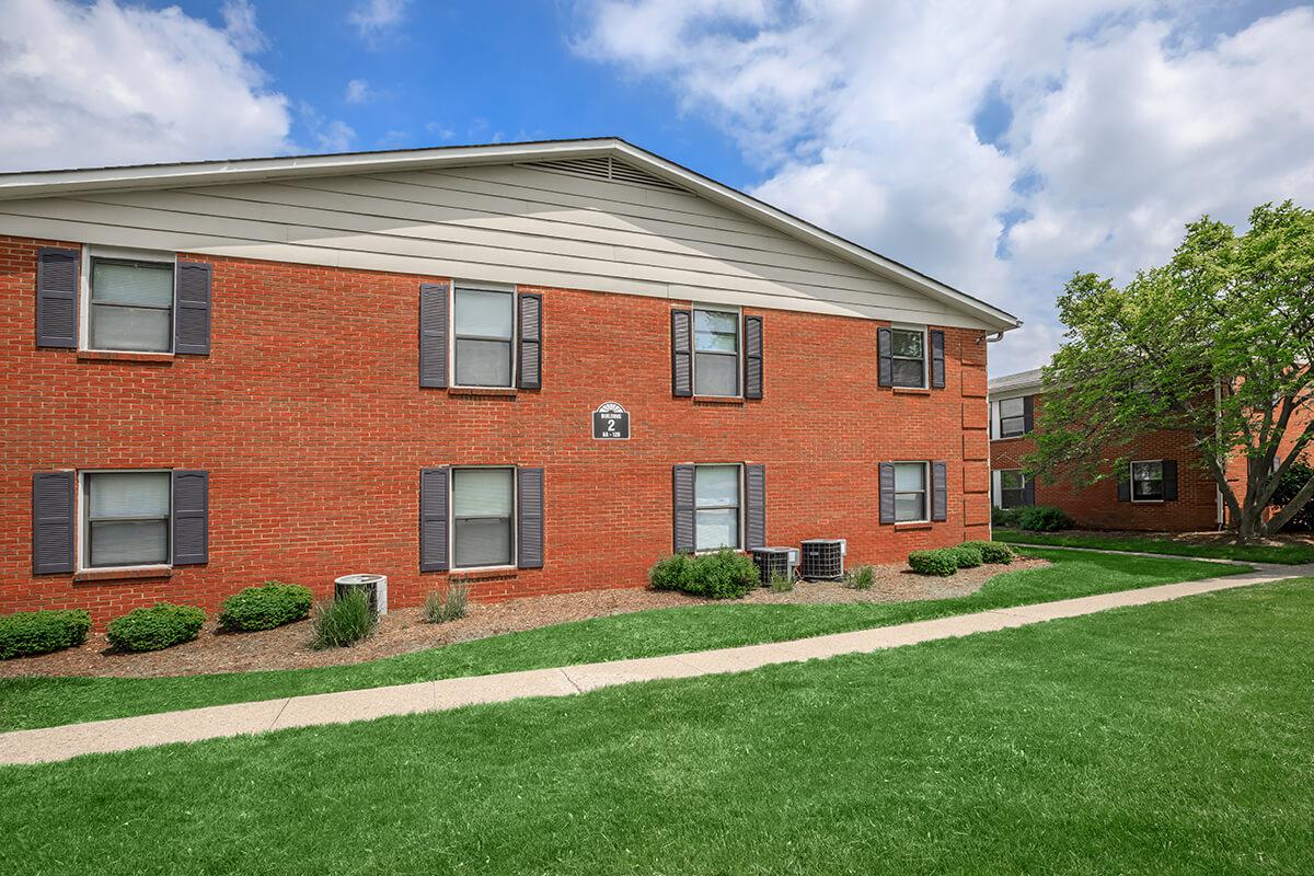 a large brick building with grass in front of a house