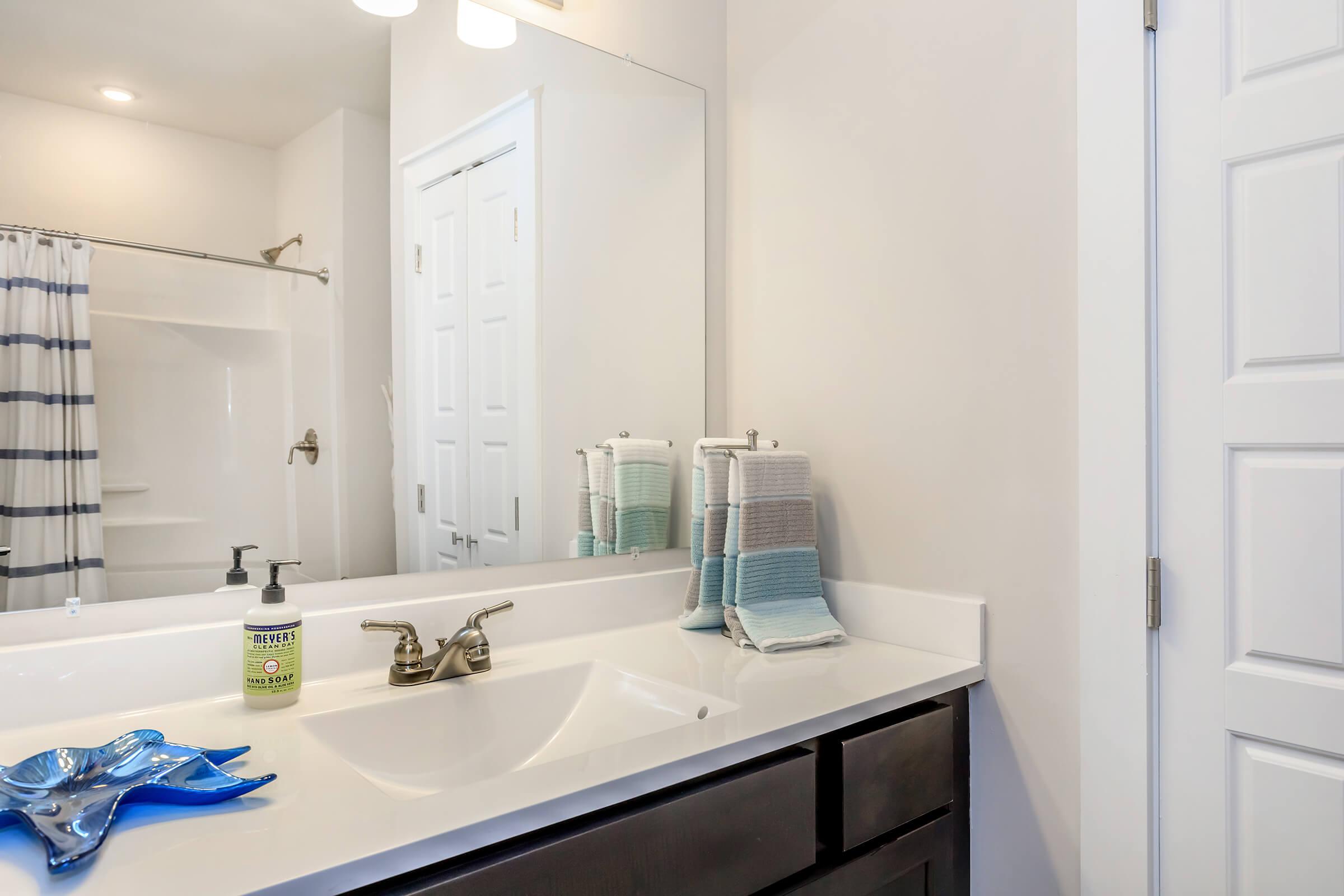 a white sink sitting under a mirror