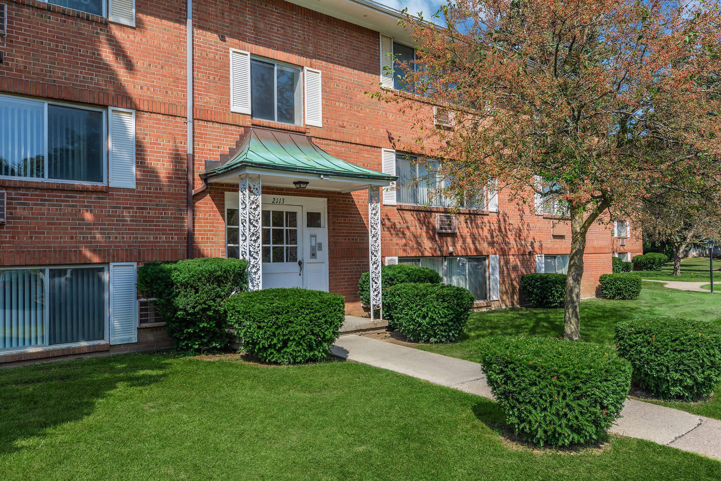 a house with bushes in front of a brick building