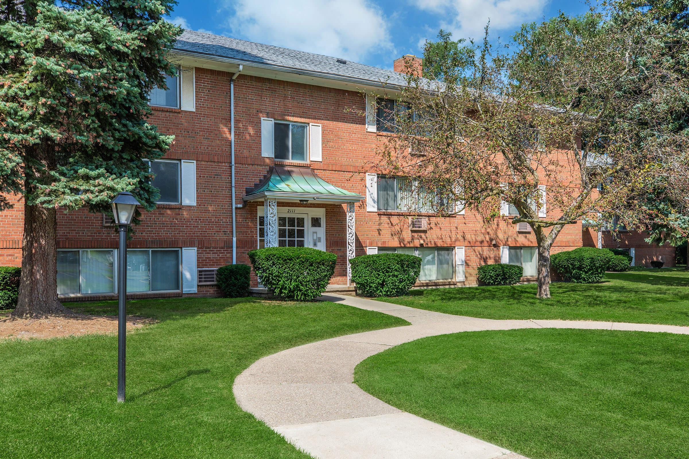 a house with a lawn in front of a brick building