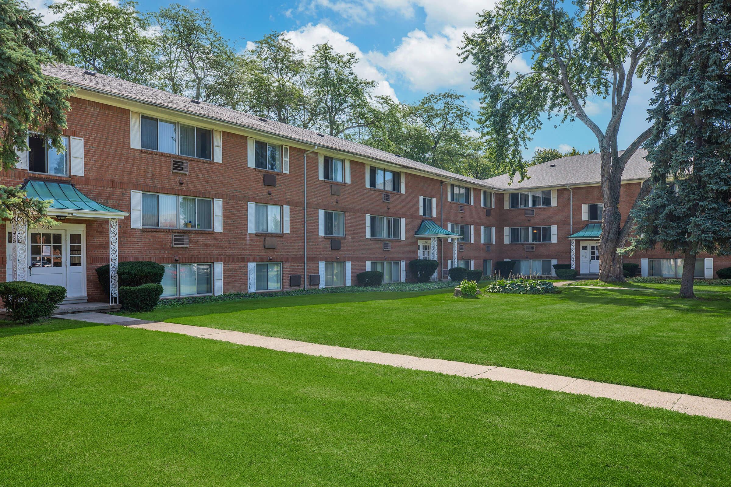 a large brick building with grass in front of a house