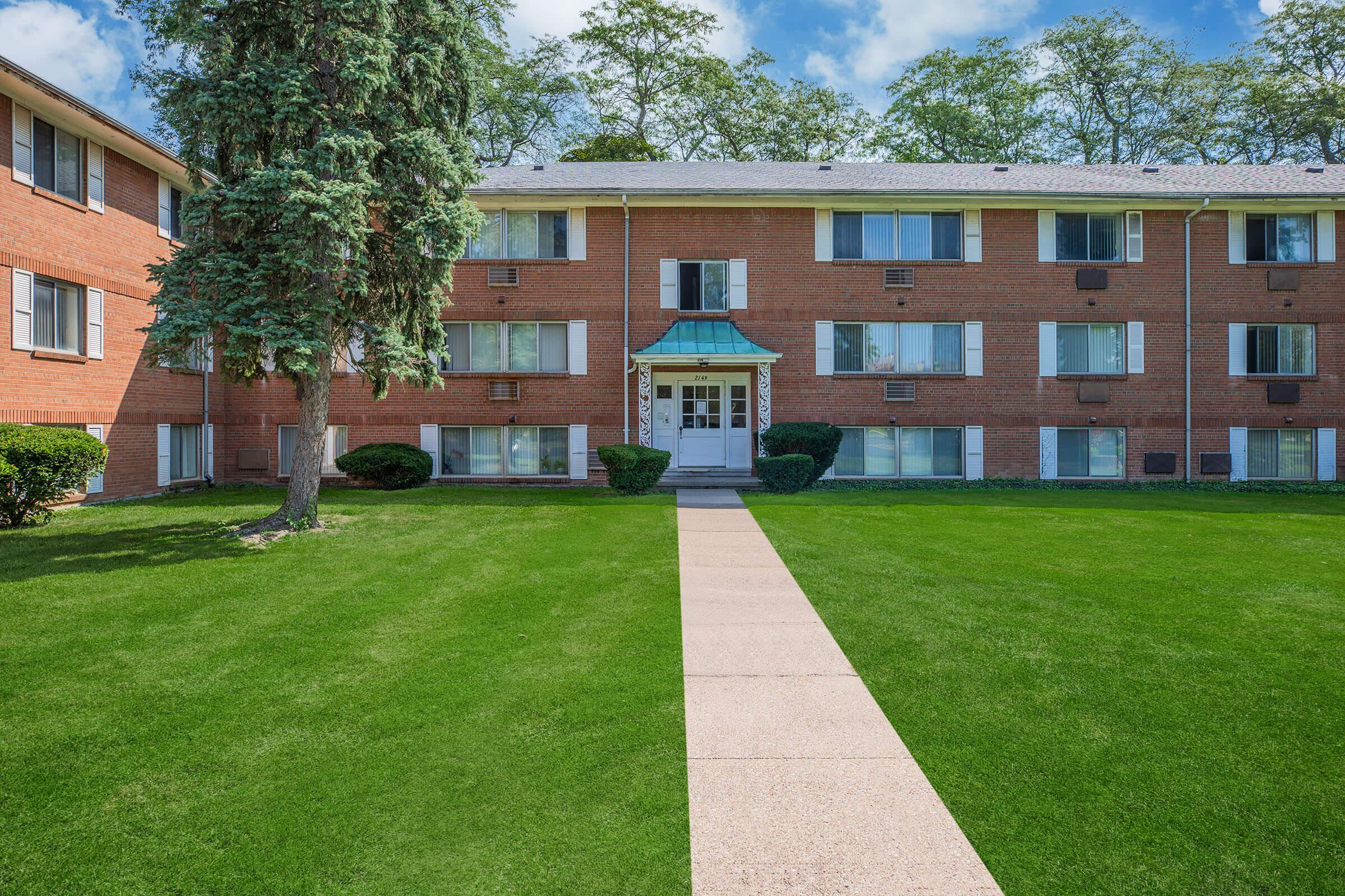 a large brick building with green grass in front of a house